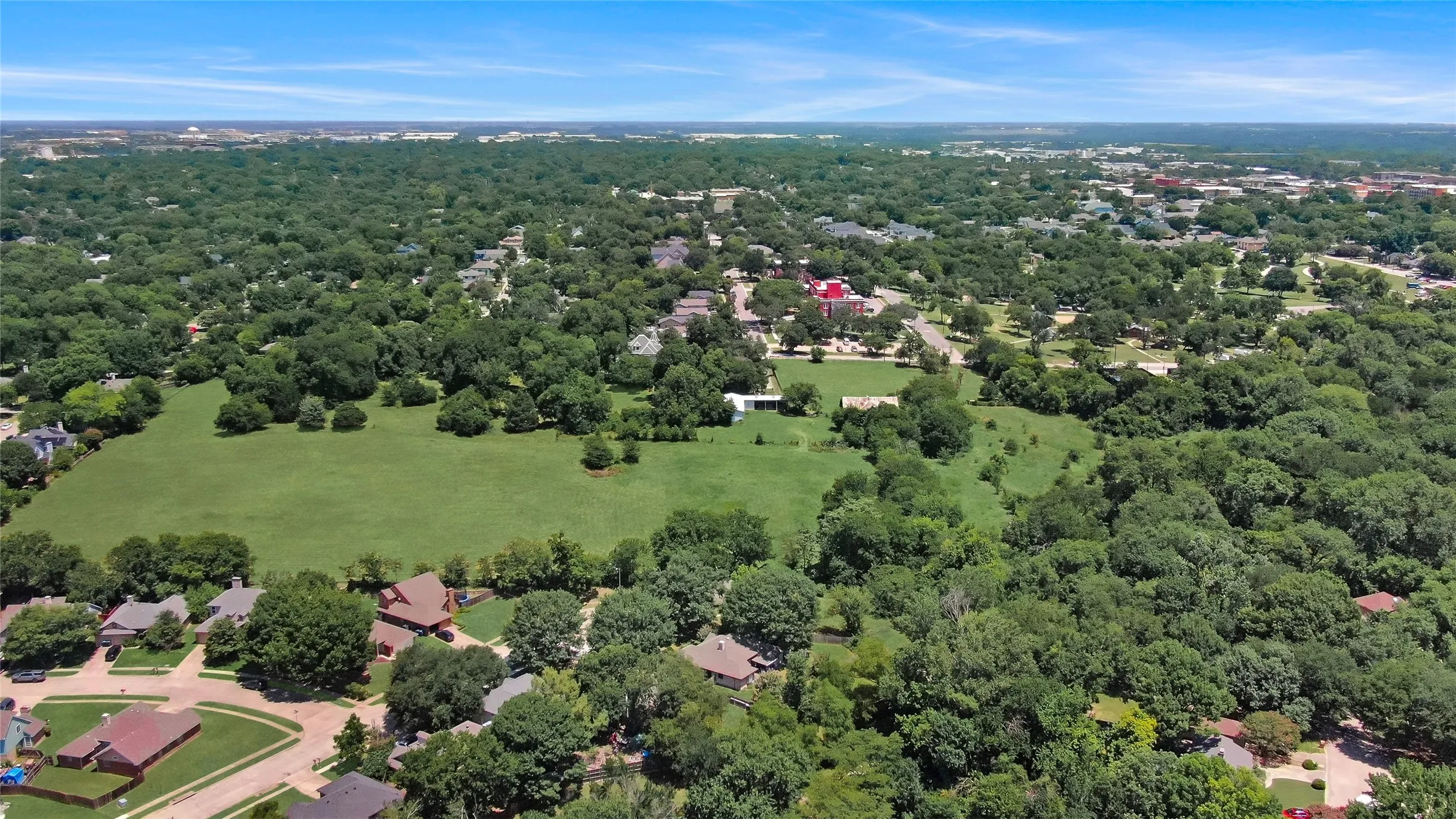 Expansive green space surrounded by mature trees and residential properties