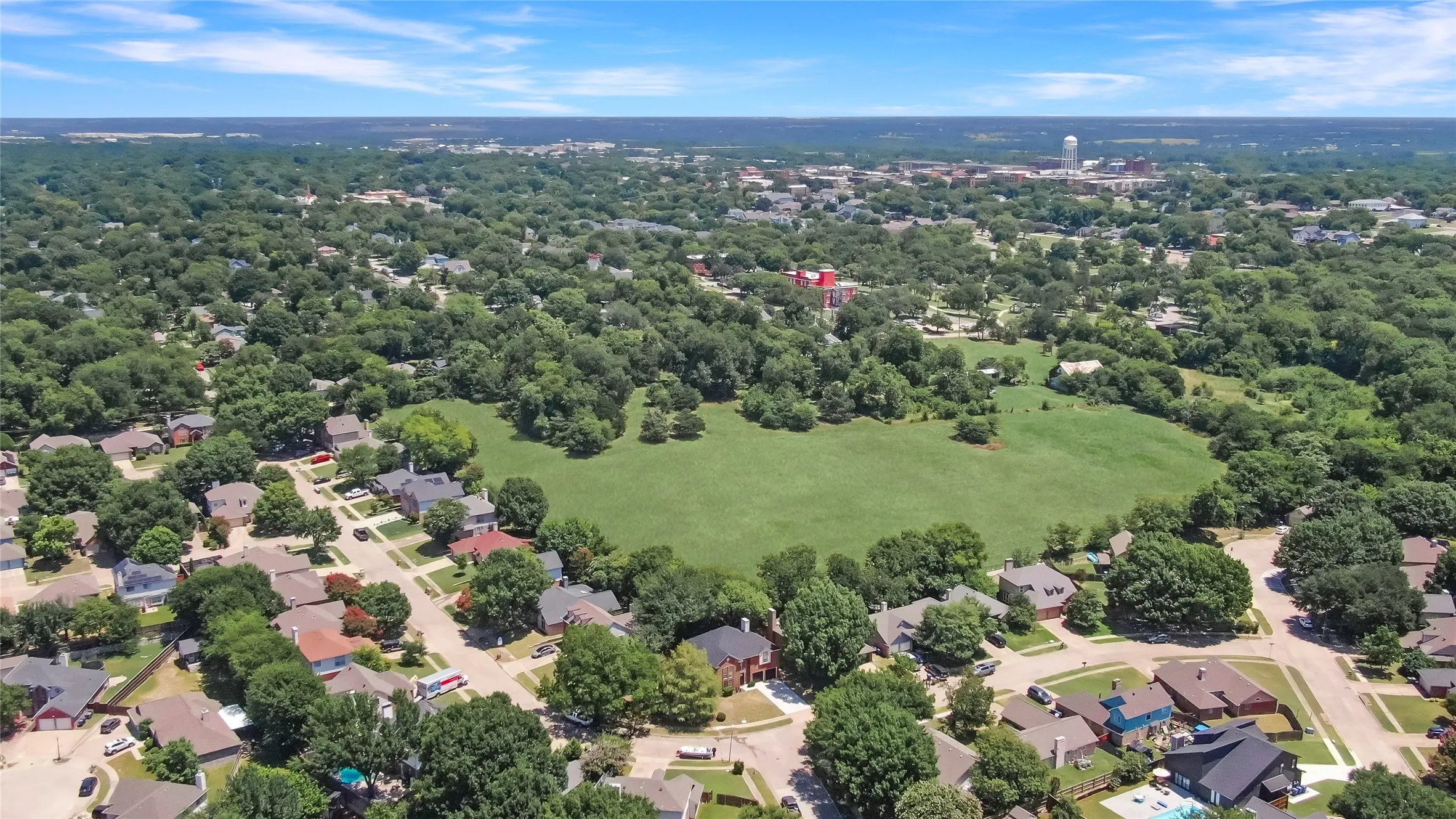 Aerial perspective of a residential area featuring a large central green space