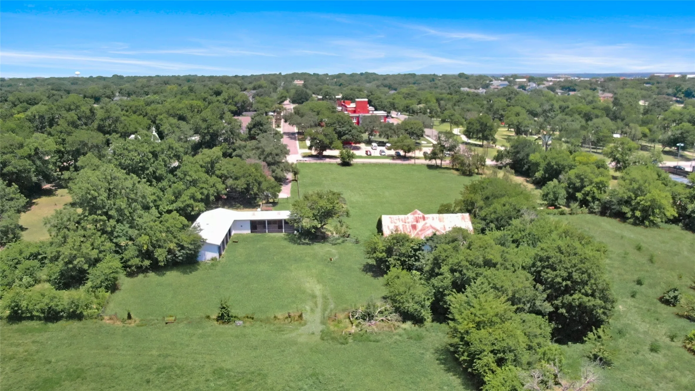 Expansive green acreage featuring two distinct structures and mature trees