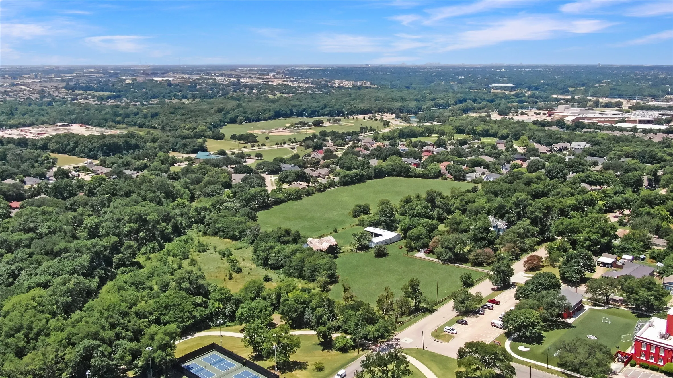 Expansive green spaces define this area, featuring mature tree coverage and open fields