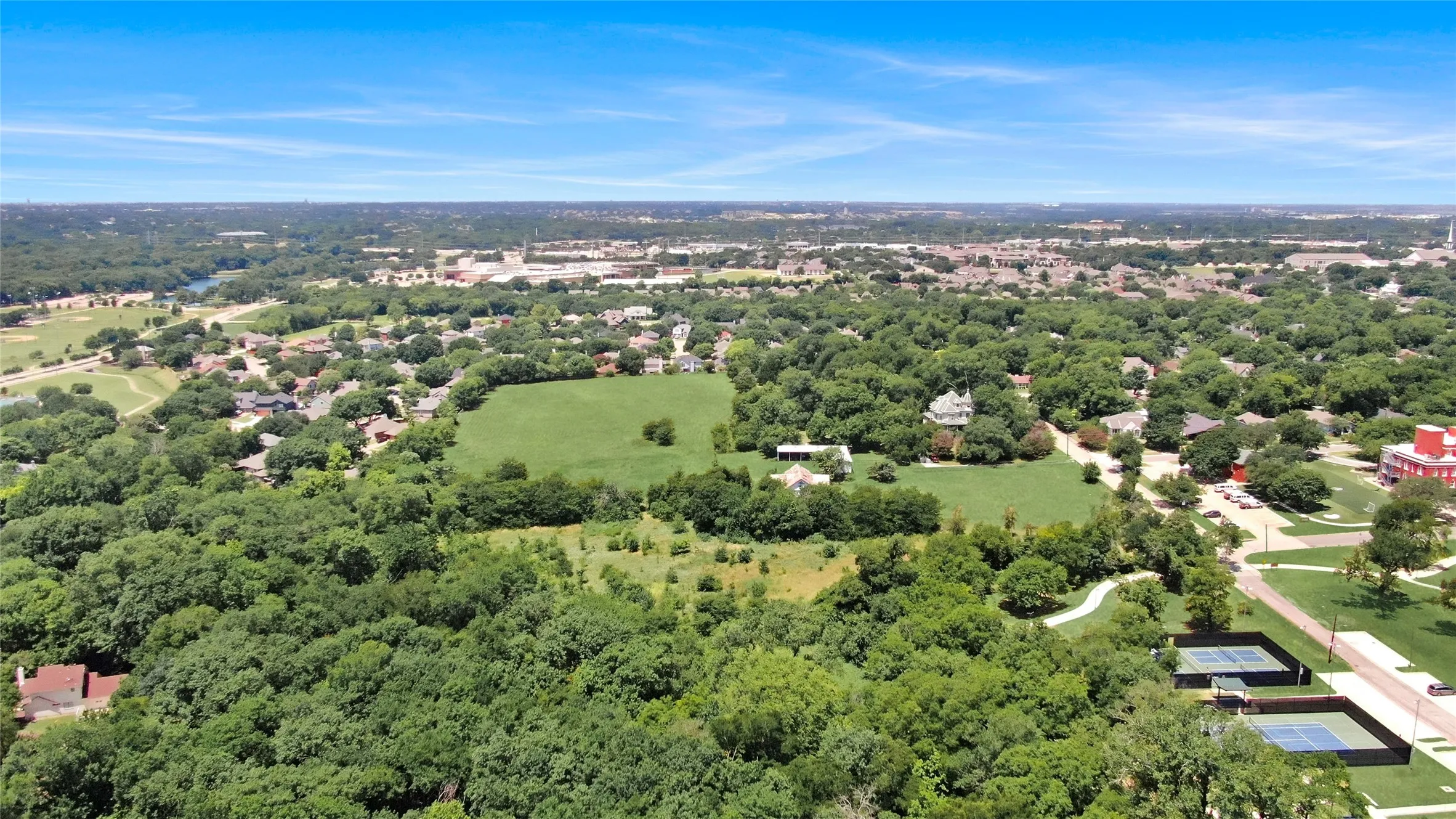 Expansive green spaces and mature tree canopy define this broad landscape
