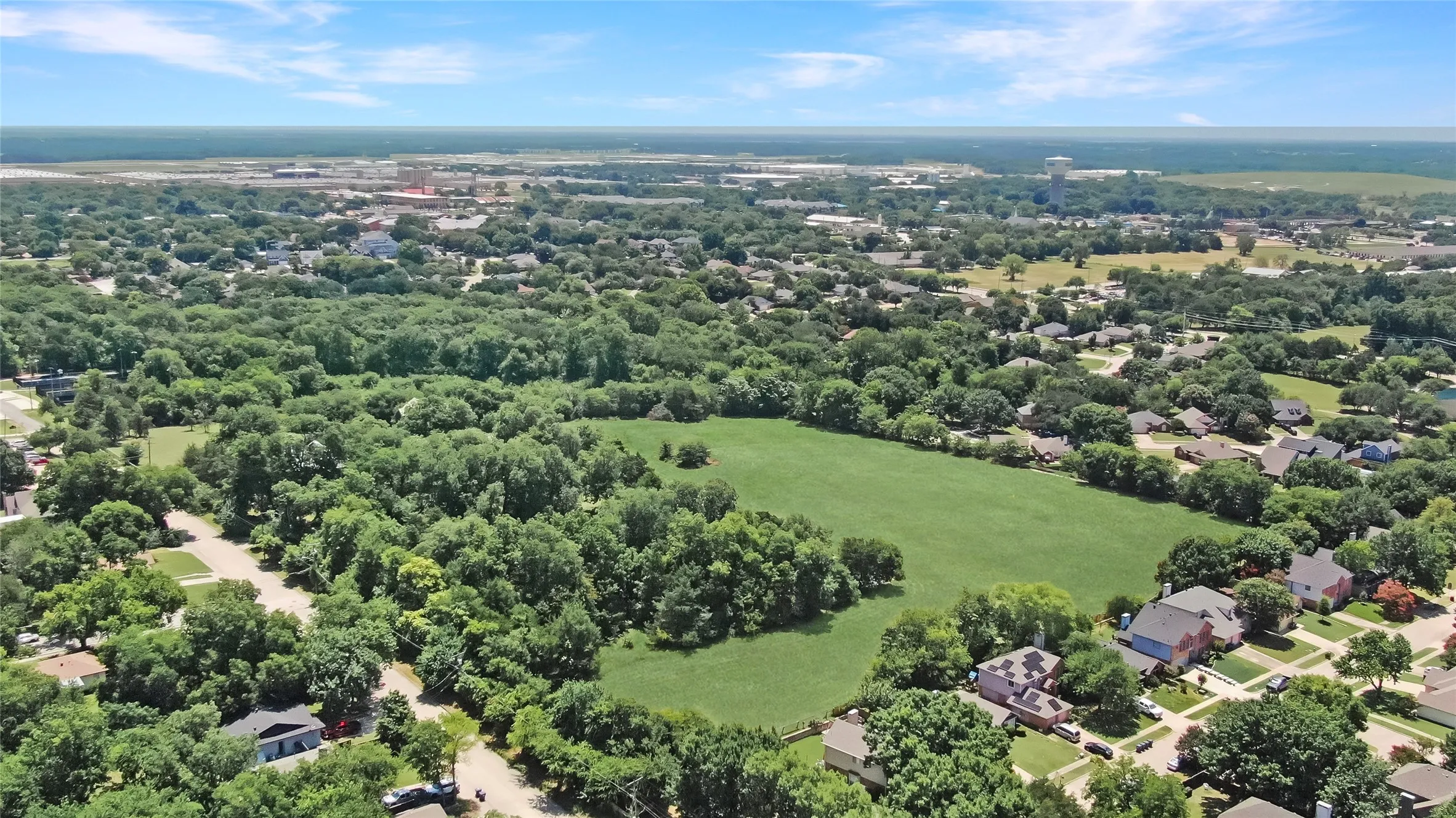 Expansive aerial perspective showcasing a verdant landscape with mature trees and a substantial open green space