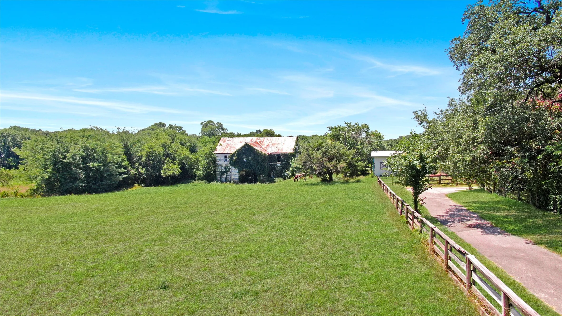 Expansive green pasture bordered by a wood rail fence