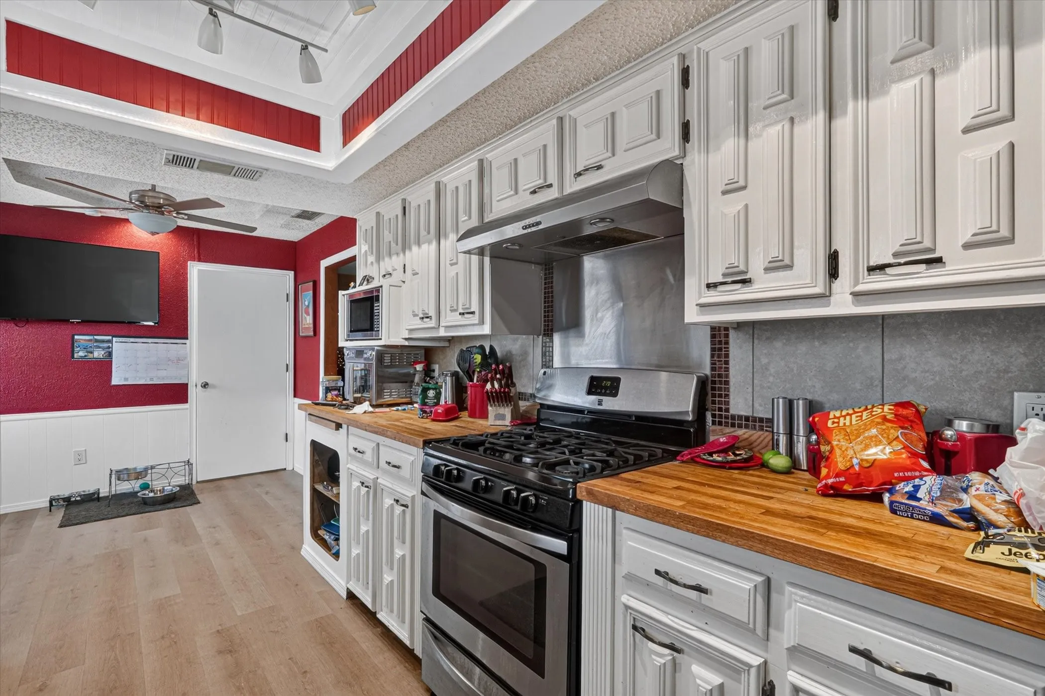 Kitchen featuring white cabinetry, wood-finish countertops, stainless steel appliances, and wood-finish flooring