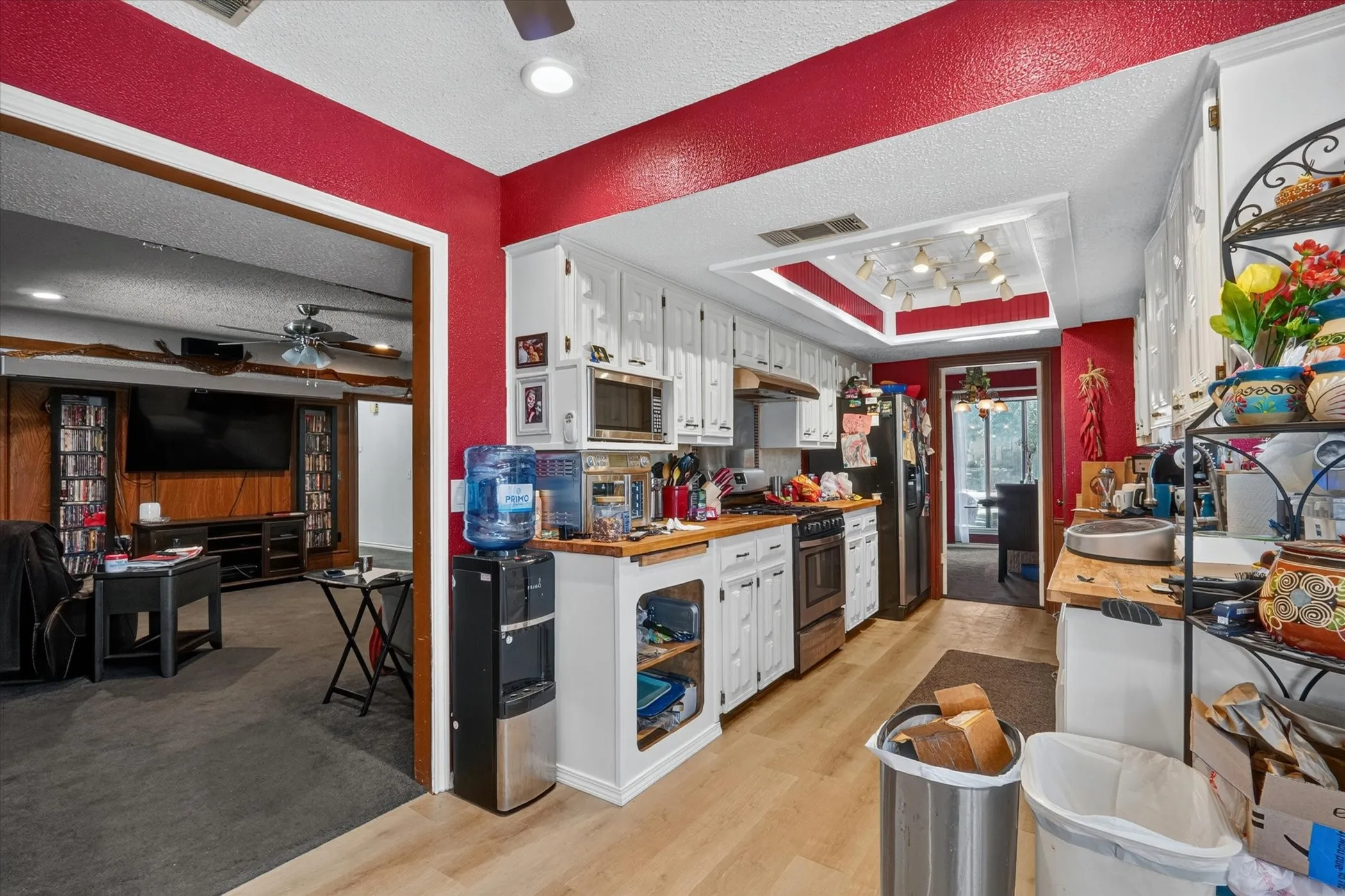 Kitchen featuring white cabinetry with brushed nickel hardware, natural wood-finish countertops, stainless steel appliances, and wood-finish flooring