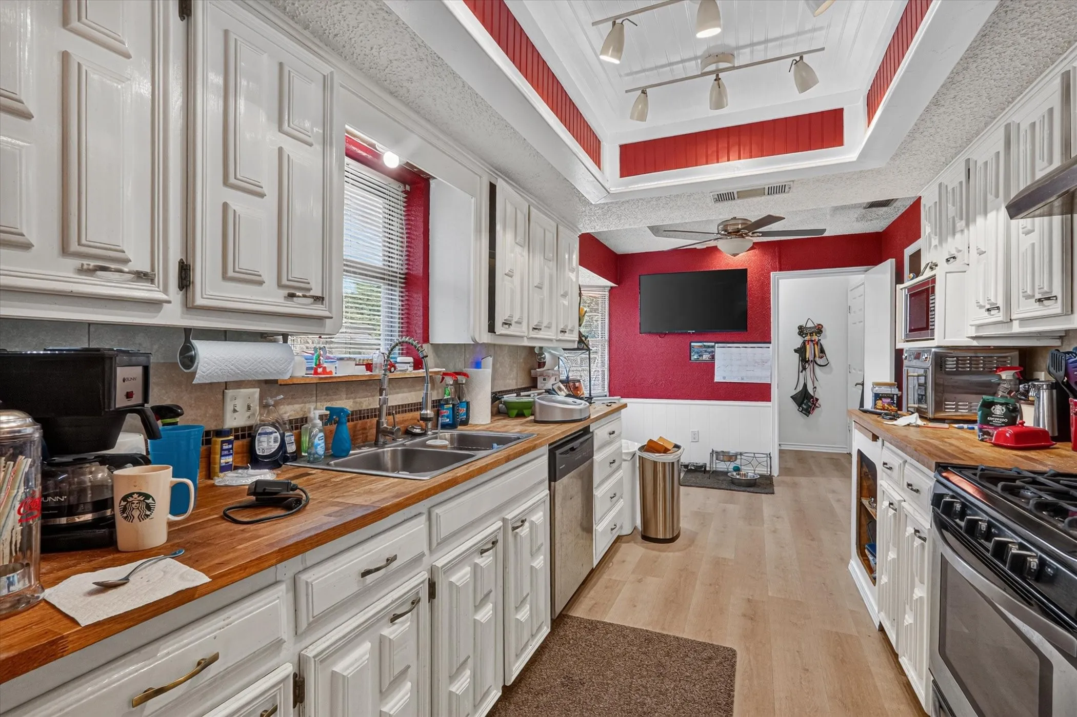 Kitchen featuring white cabinetry, butcher block countertops, stainless steel appliances, and wood-finish flooring