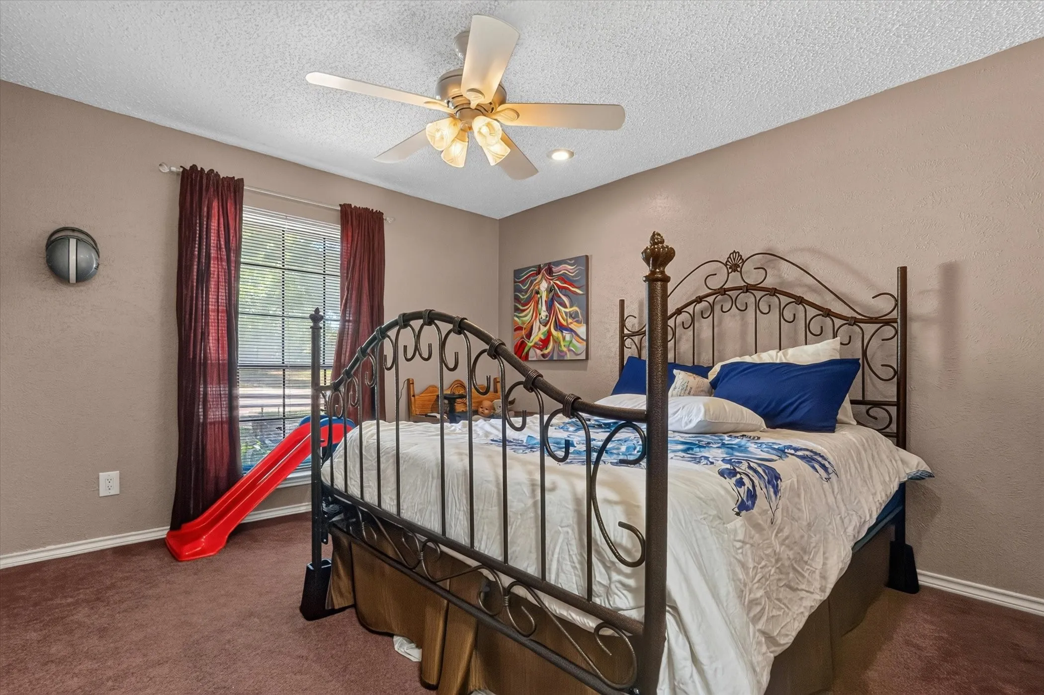 Spacious room featuring a ceiling fan with integrated lighting, wall-to-wall carpeting, and a window with natural light