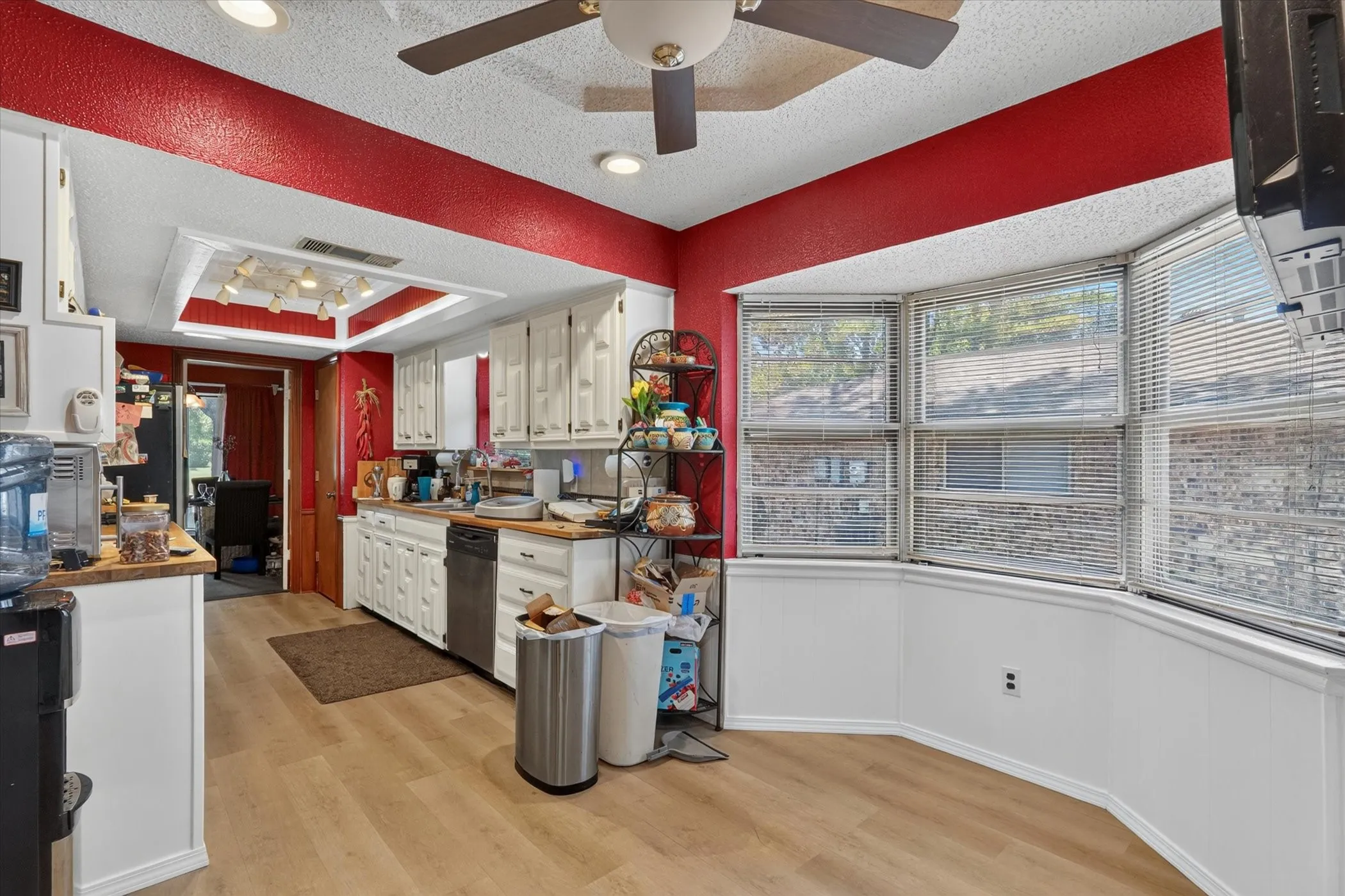Kitchen featuring light wood-finish flooring, white cabinetry, and a bay window