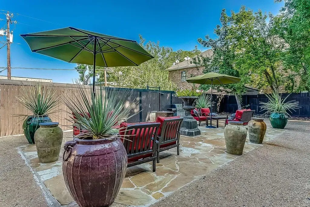 Expansive stone patio featuring a flagstone surface, large decorative planters, and a privacy fence
