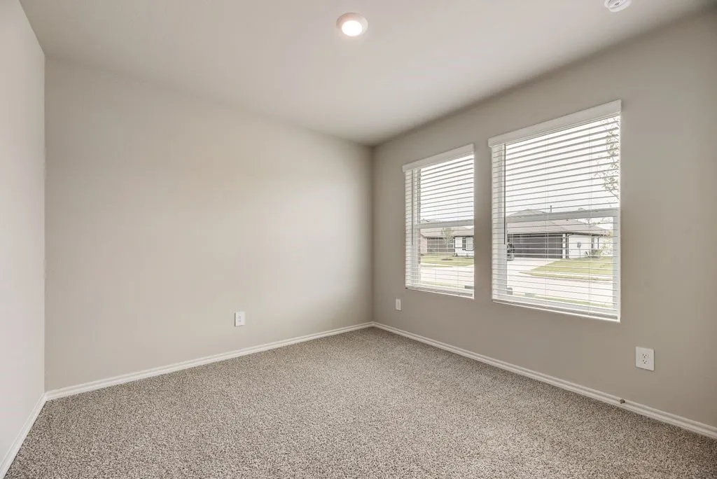Neutral-toned room featuring two windows with horizontal blinds, providing natural light