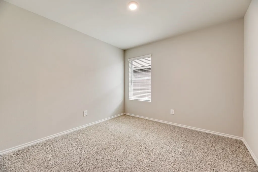 Room featuring neutral-toned walls, textured carpeting, a single window with horizontal blinds, and a recessed ceiling light fixture