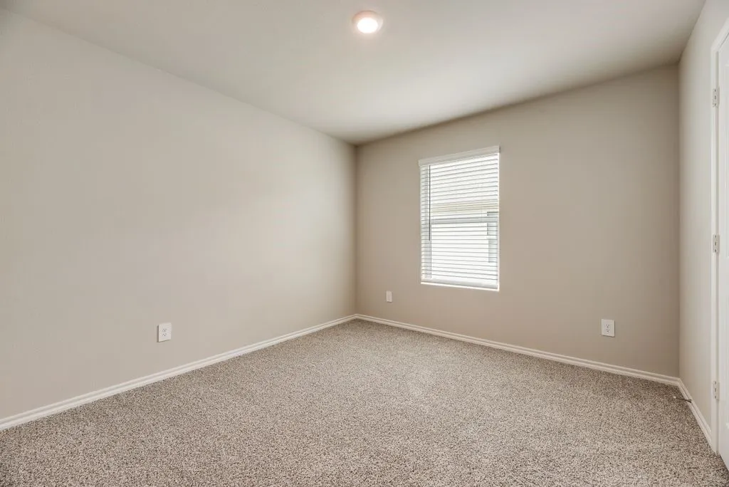 Carpeted room with neutral wall tones and a window featuring horizontal blinds