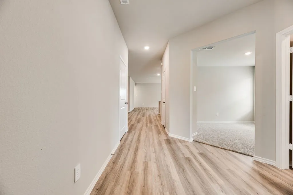 Hallway with wood-finish flooring, recessed lighting, and crisp white trim