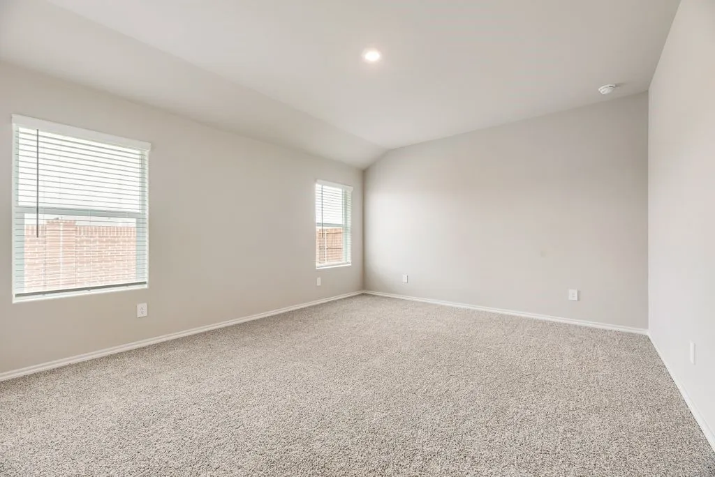 Spacious room featuring neutral paint, two windows with blinds, a vaulted ceiling, recessed lighting, and plush carpet