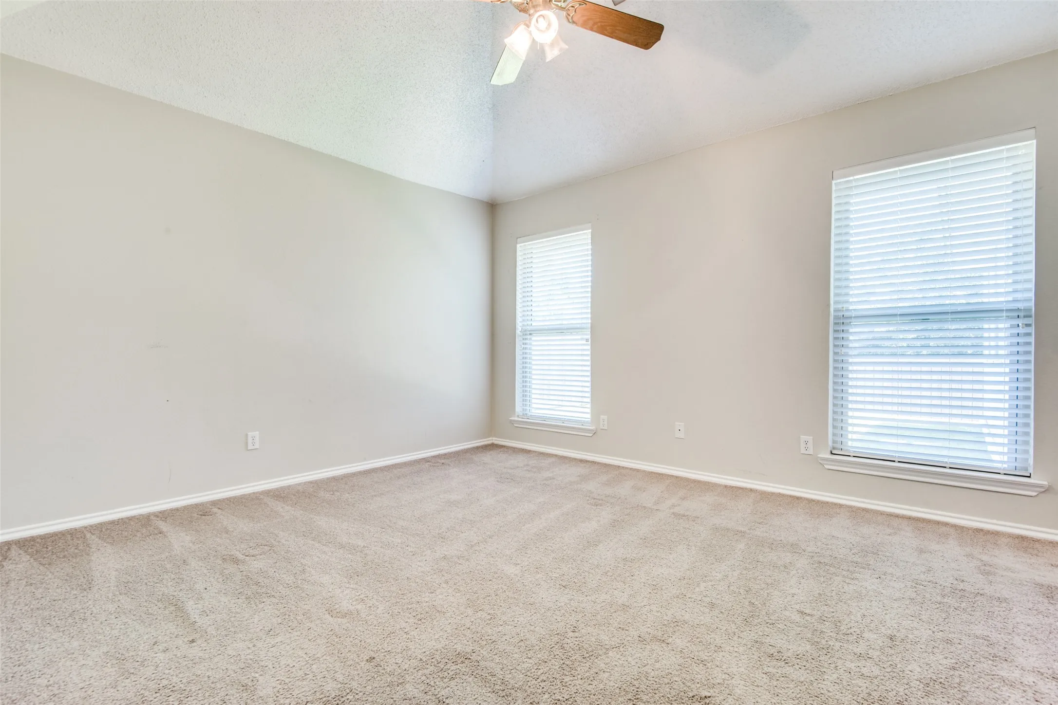 Carpeted room featuring a vaulted ceiling with a ceiling fan