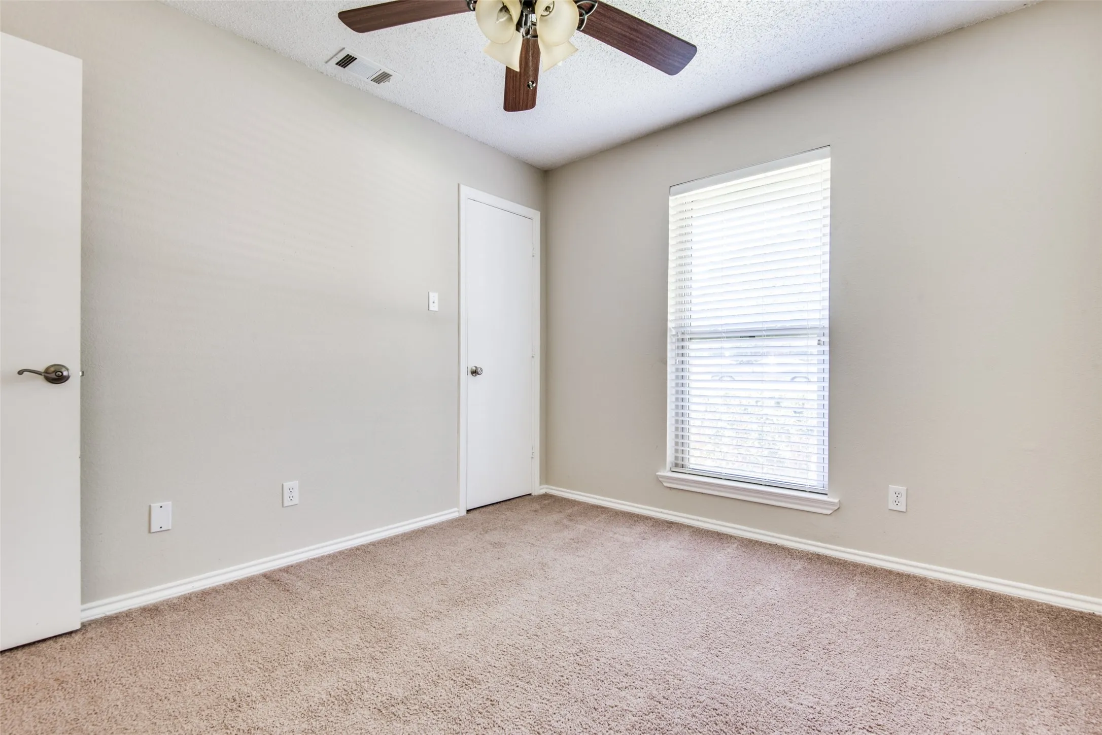 Carpeted room featuring a ceiling fan with light fixture, a window with horizontal blinds, and light-toned wall paint