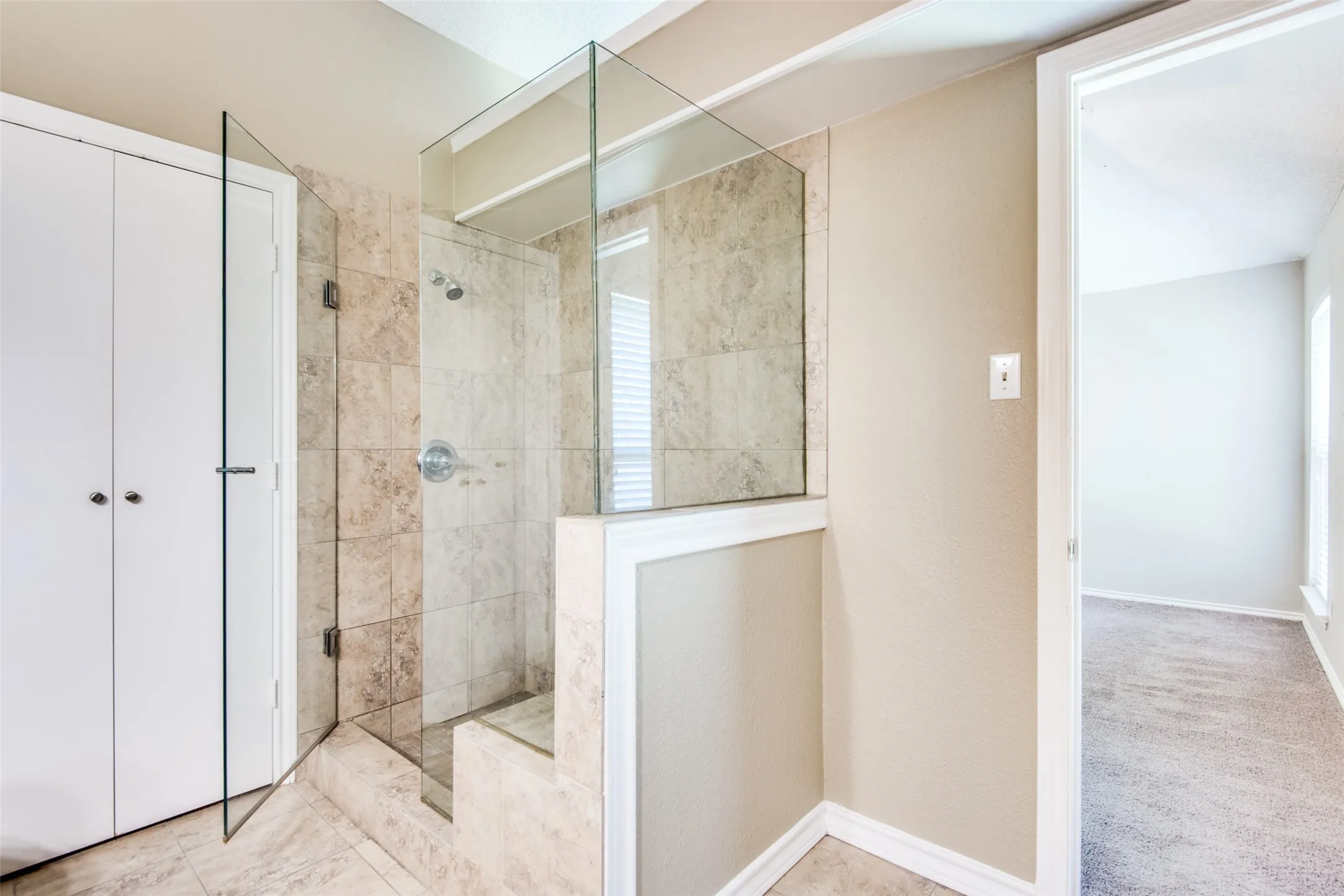 Walk-in shower featuring glass enclosure, tiled walls, and a built-in bench