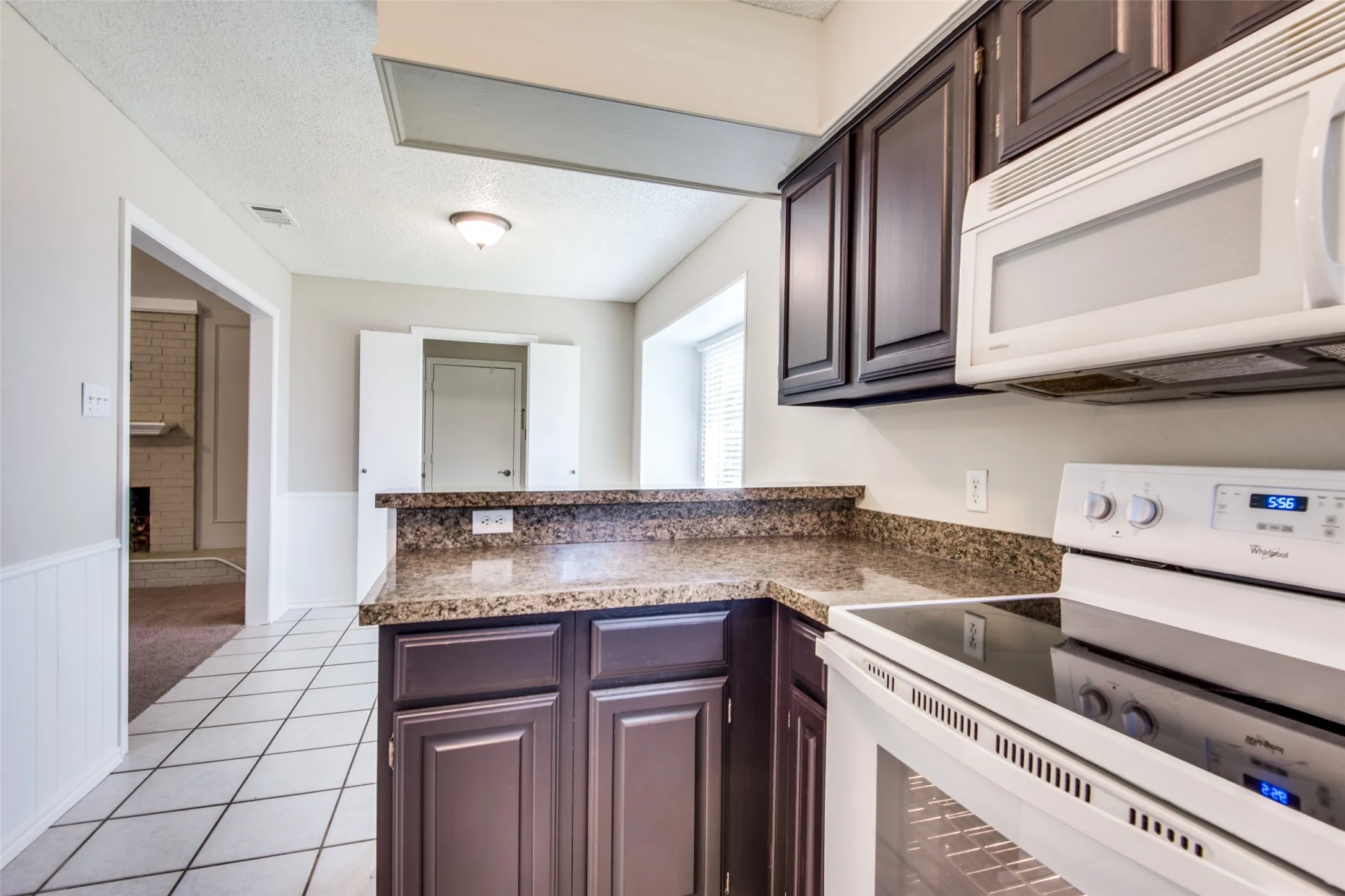 Kitchen featuring dark wood cabinetry, a built-in microwave, and a white electric range