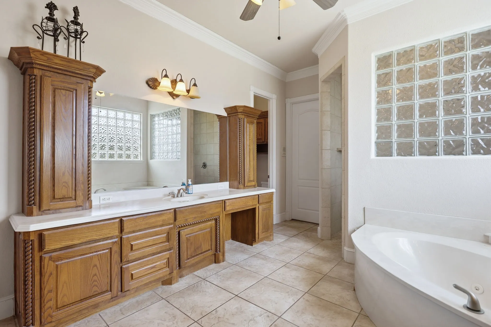 Expansive vanity with wood-finish cabinetry, dual sinks, and white countertops