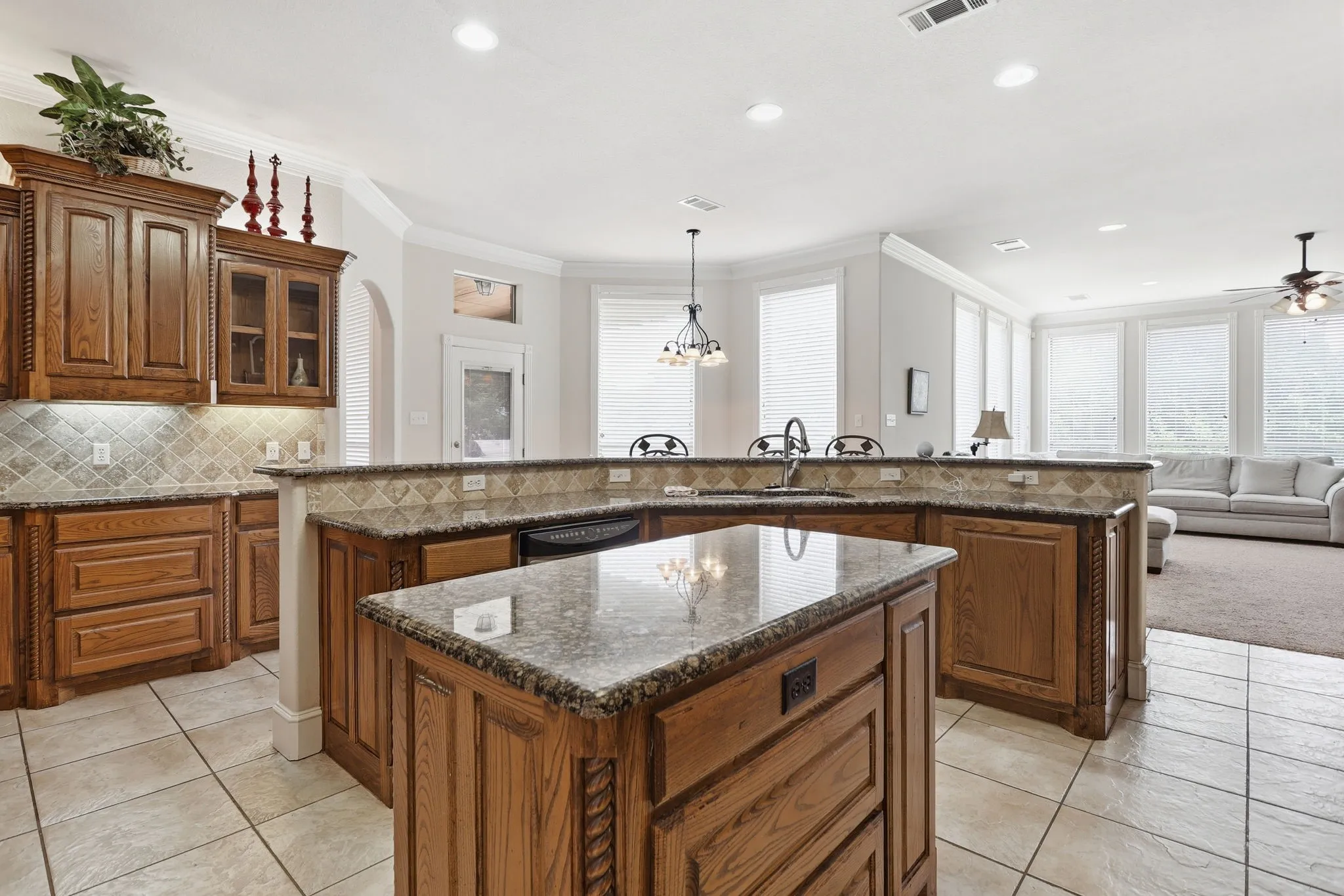 Kitchen featuring a central island with a stone-finish countertop, wood cabinetry, and a tile backsplash