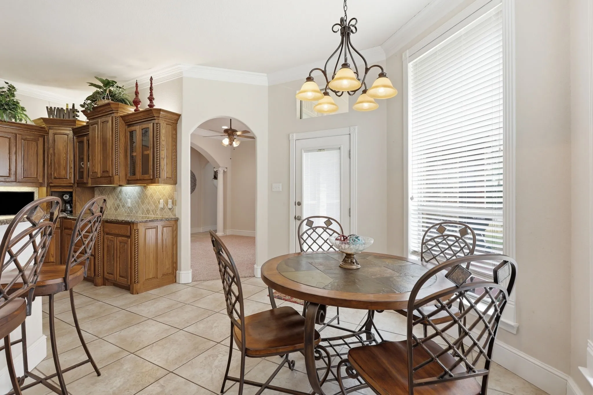 Kitchen dining area featuring a pendant chandelier, large window with blinds, and tile flooring