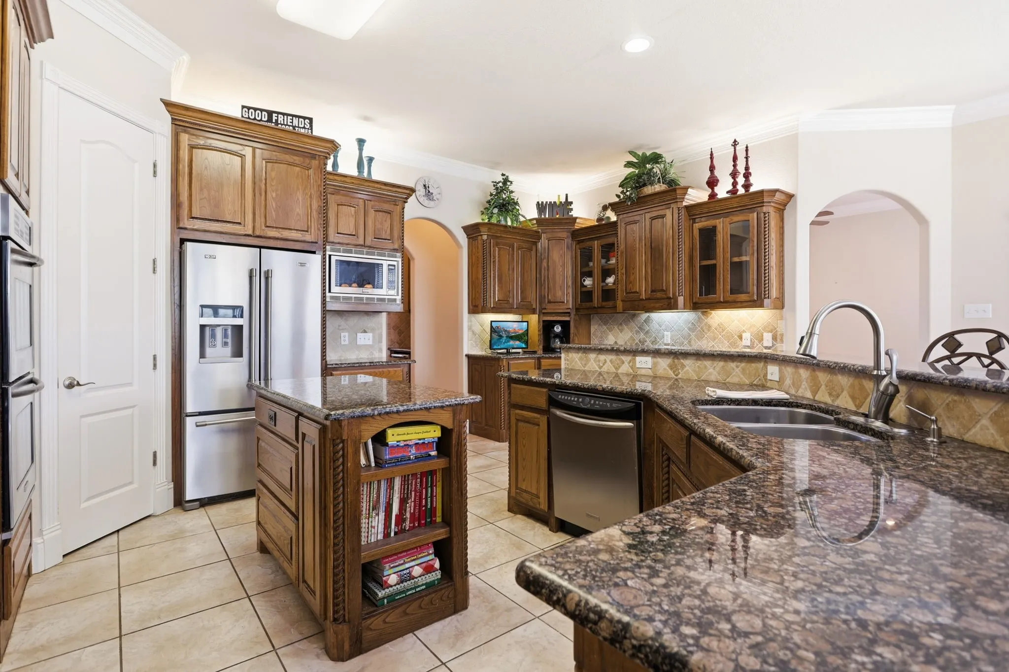Kitchen featuring granite countertops, wood cabinetry, stainless steel appliances, a tile backsplash, and a center island
