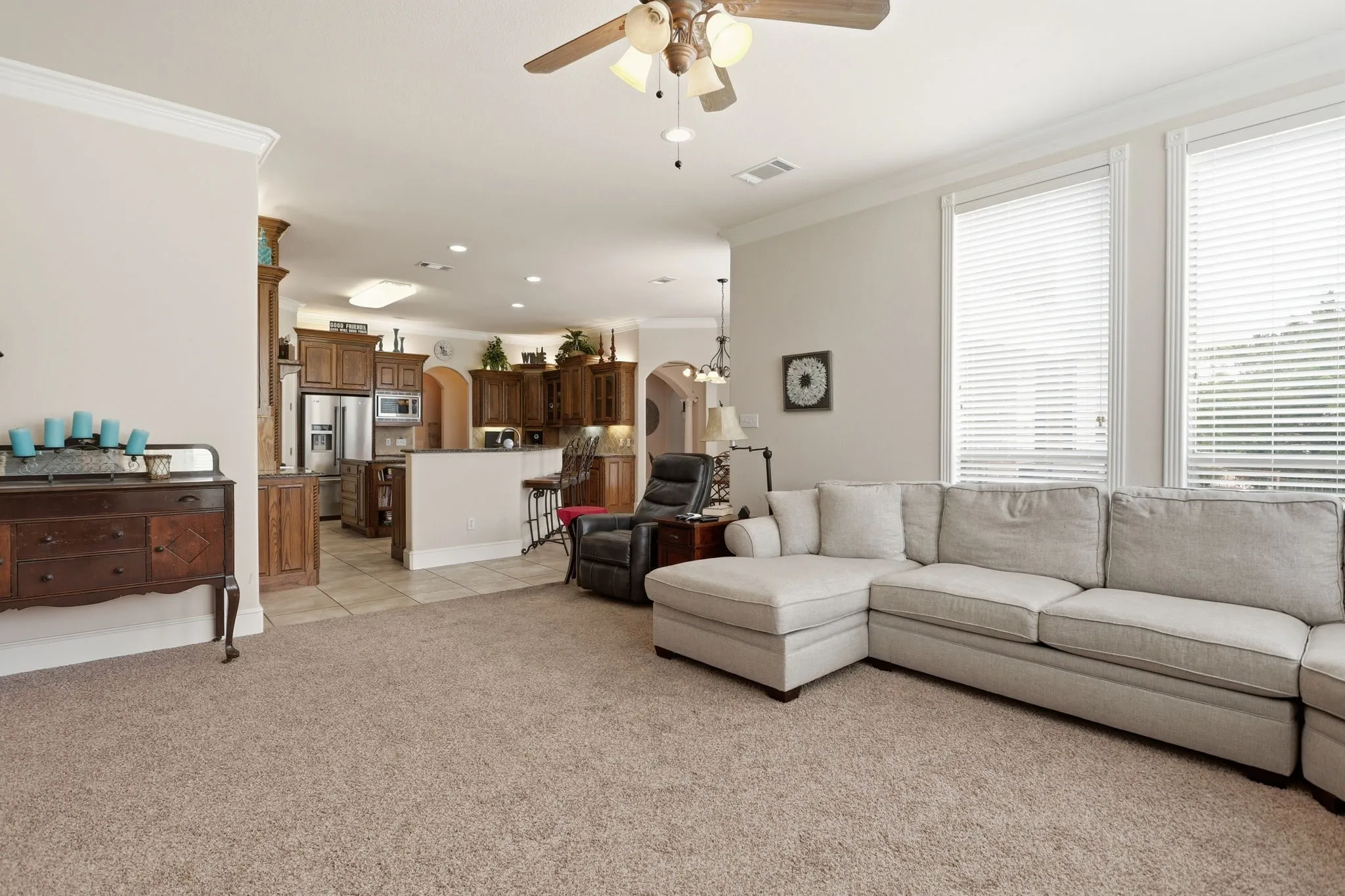 Open-concept living space featuring carpet flooring and crown molding