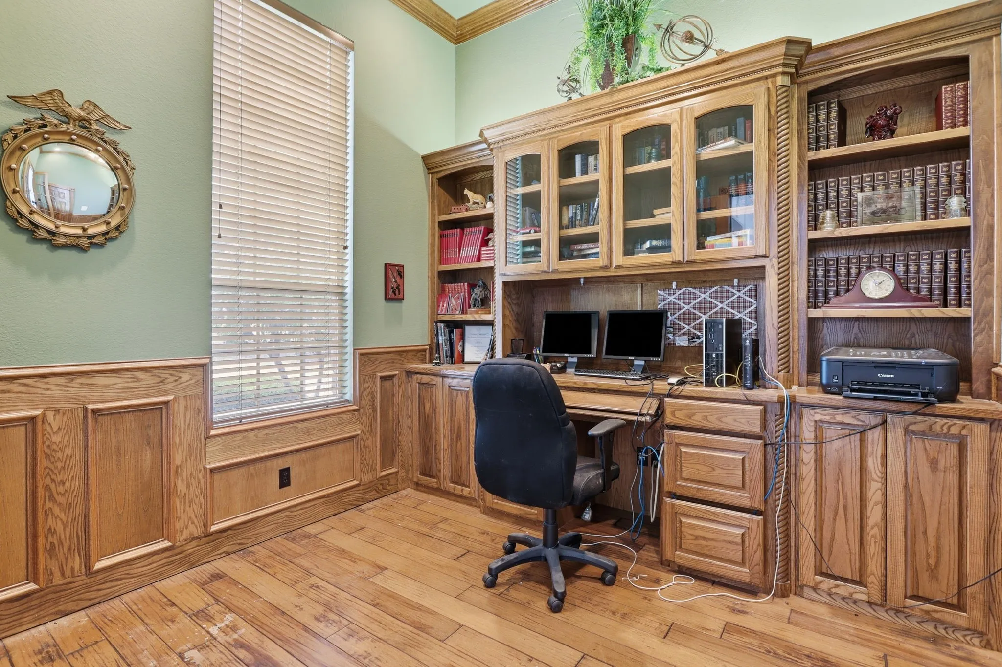 Dedicated office space featuring extensive built-in custom cabinetry, integrated desk area, and wood-finish flooring