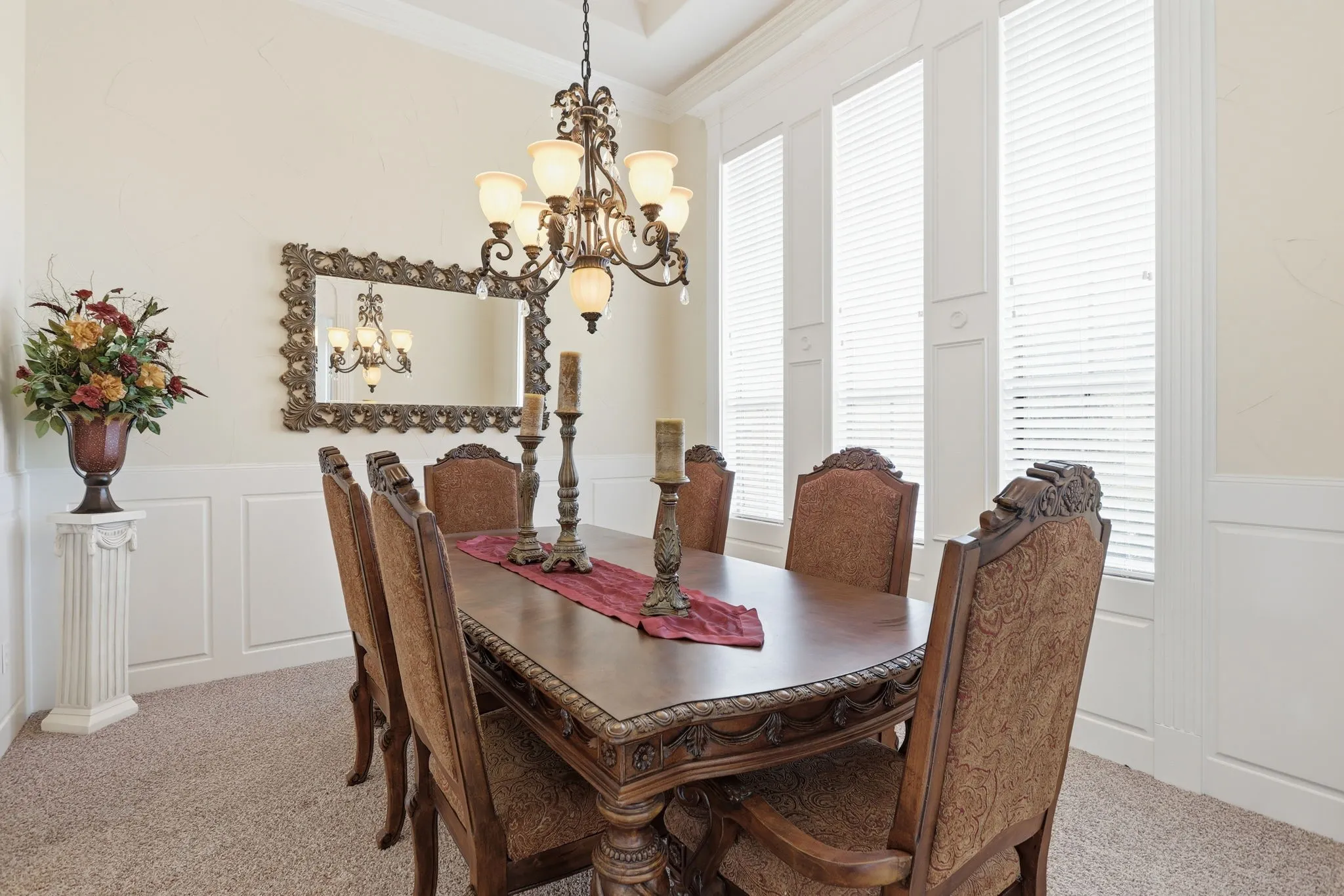 Formal dining area featuring a decorative chandelier, wainscoting, crown molding, and multiple tall windows