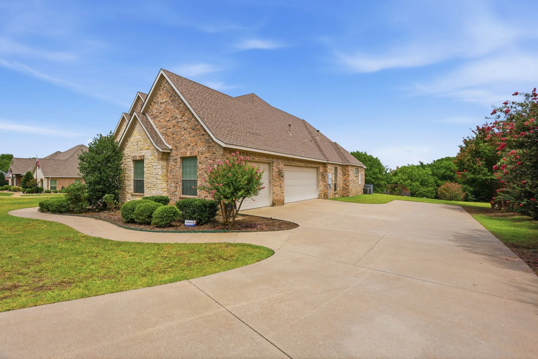 Brick and stone exterior with architectural gables, a two-car garage, and a concrete driveway