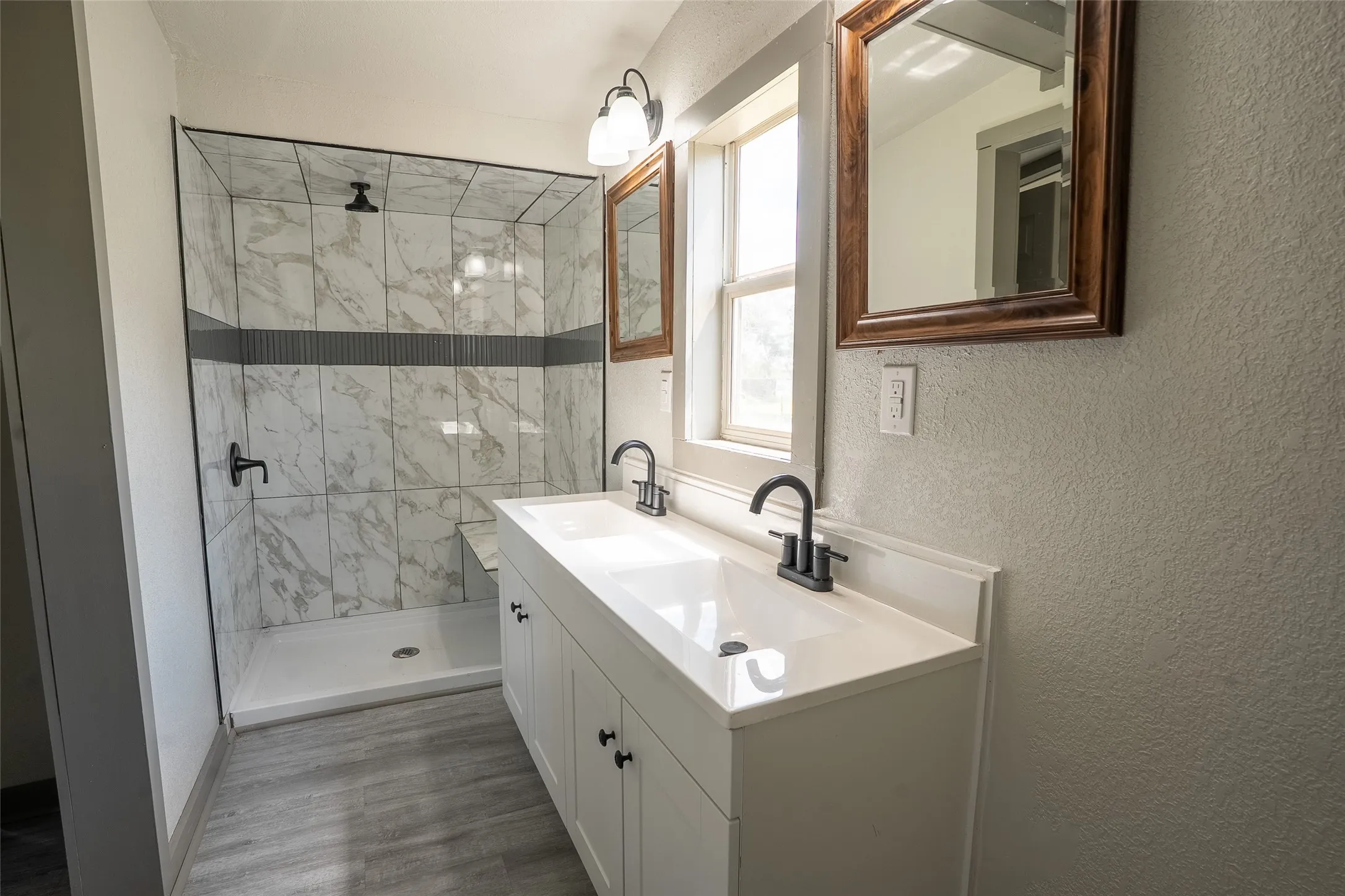 Bathroom featuring a dual sink vanity with white cabinetry, matte black fixtures, and a framed mirror