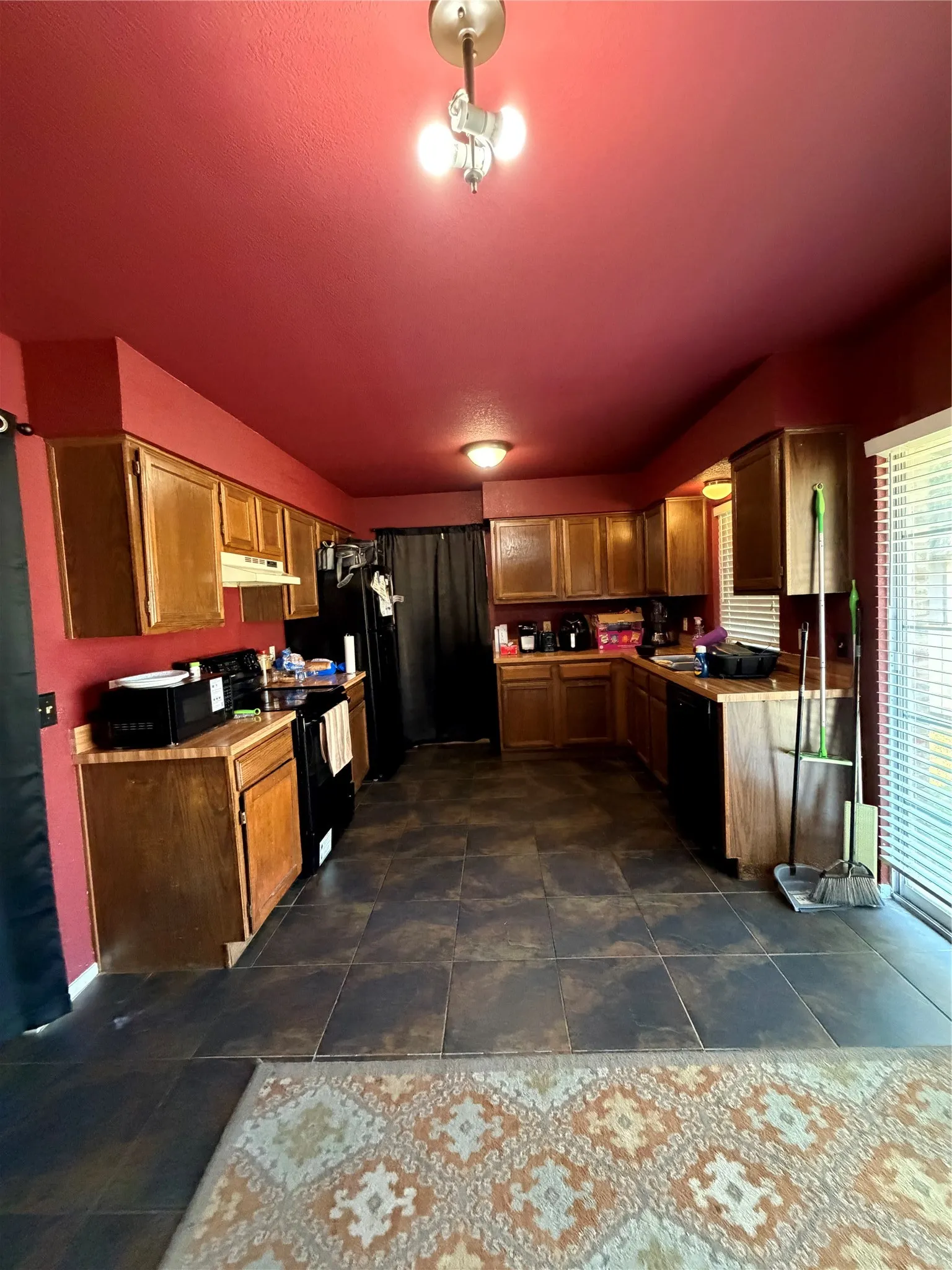 U-shaped kitchen featuring wood cabinetry, dark-finish appliances, and tile flooring