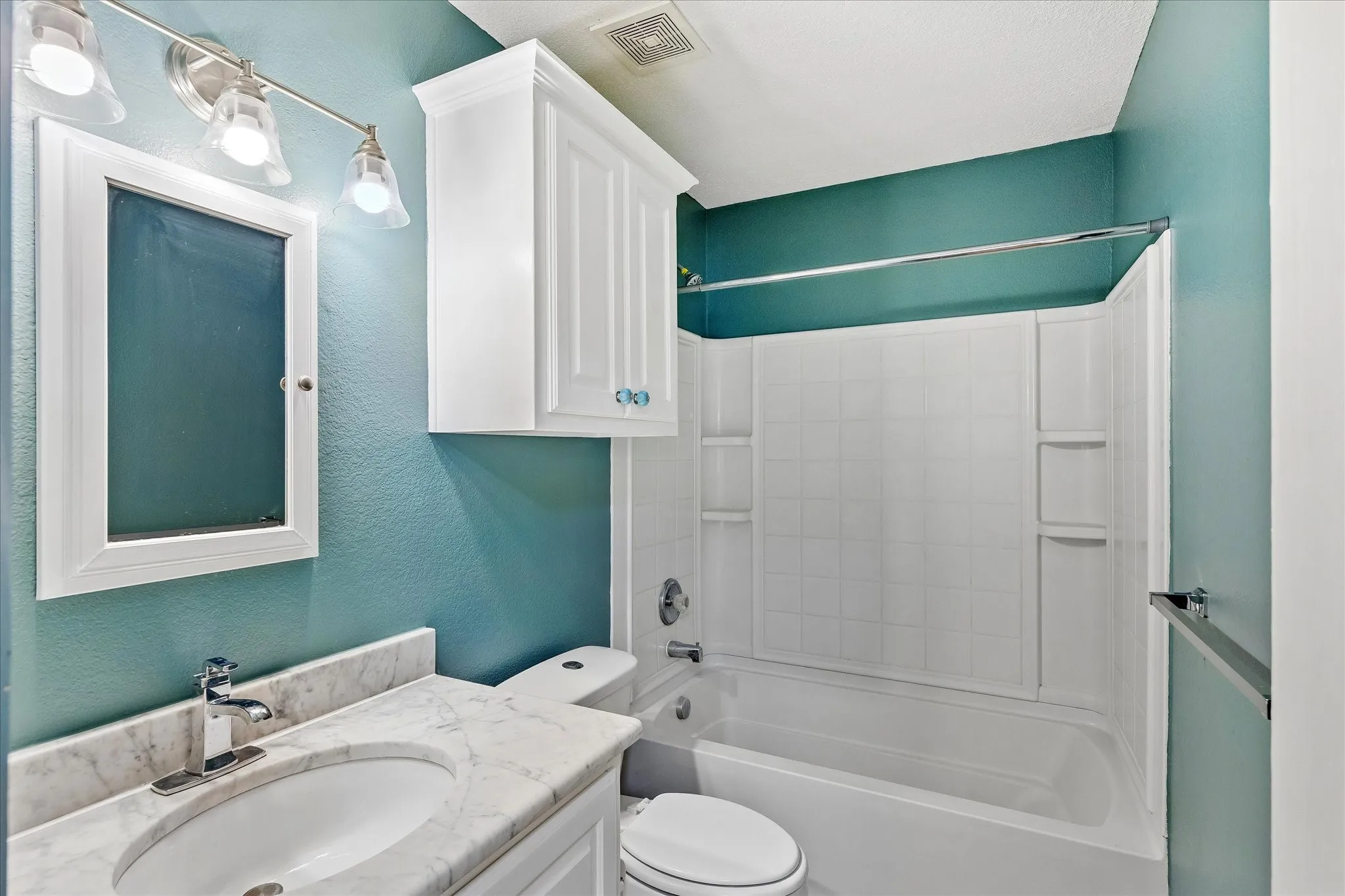 Bathroom featuring a white vanity with a stone countertop and integrated sink, chrome faucet, and framed mirror