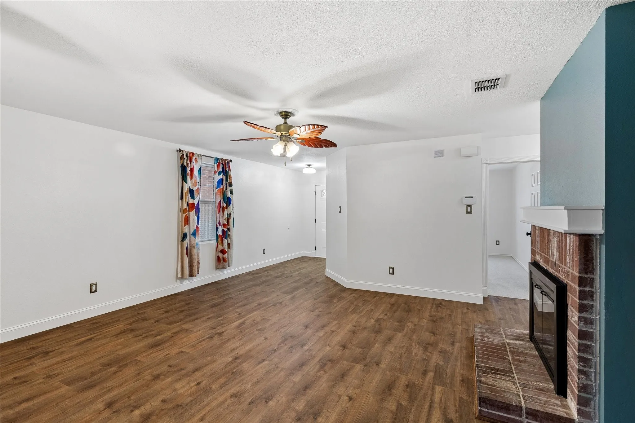 Living area featuring wood-finish flooring, a ceiling fan, and white baseboards