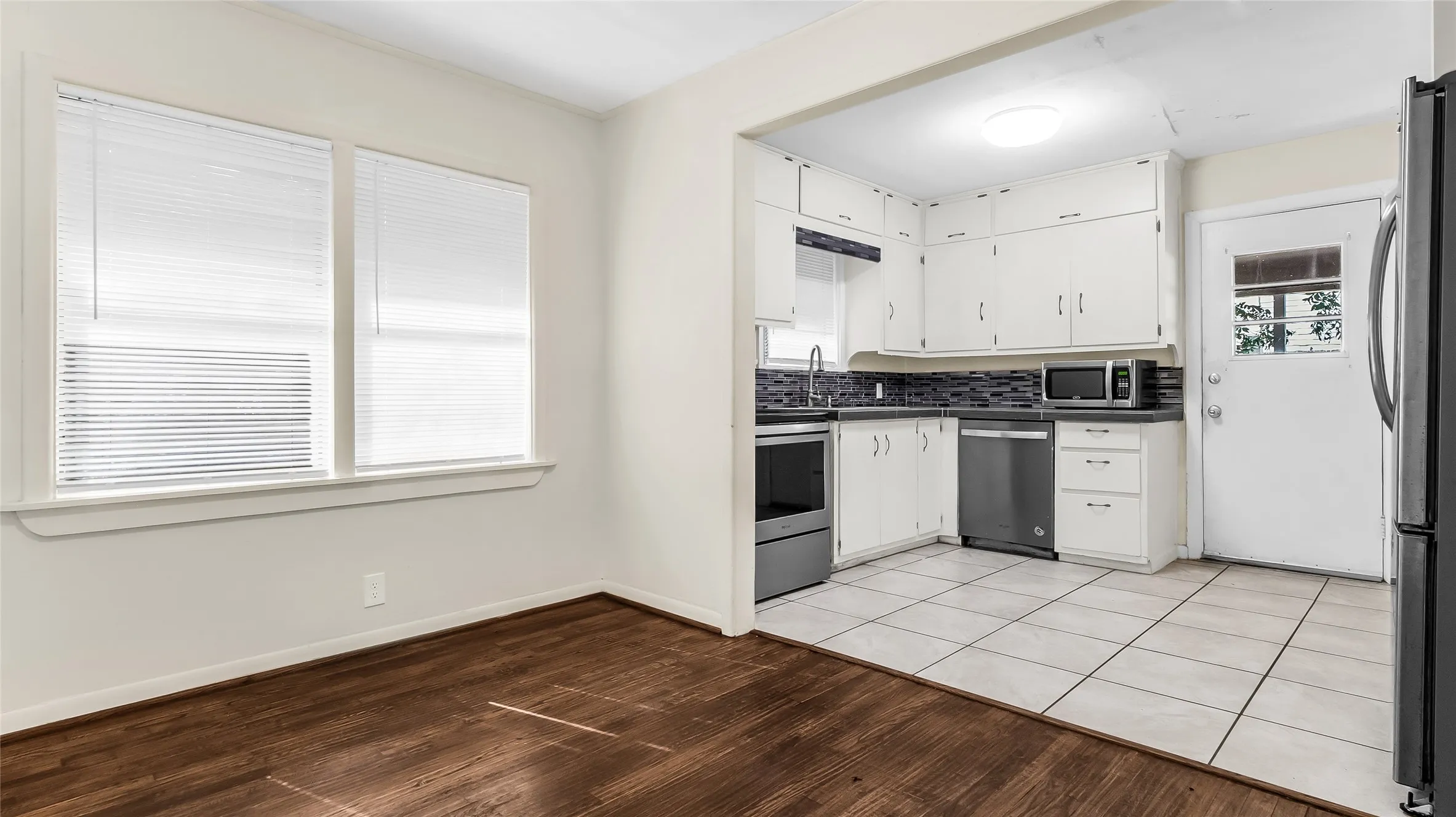 Kitchen featuring white cabinetry, dark countertops, and a subway tile backsplash