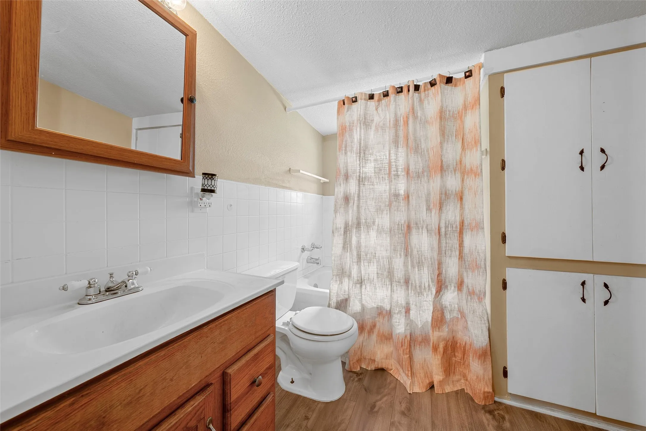 Bathroom featuring a wood-finish vanity with an integrated sink, white subway tile backsplash, and a framed medicine cabinet