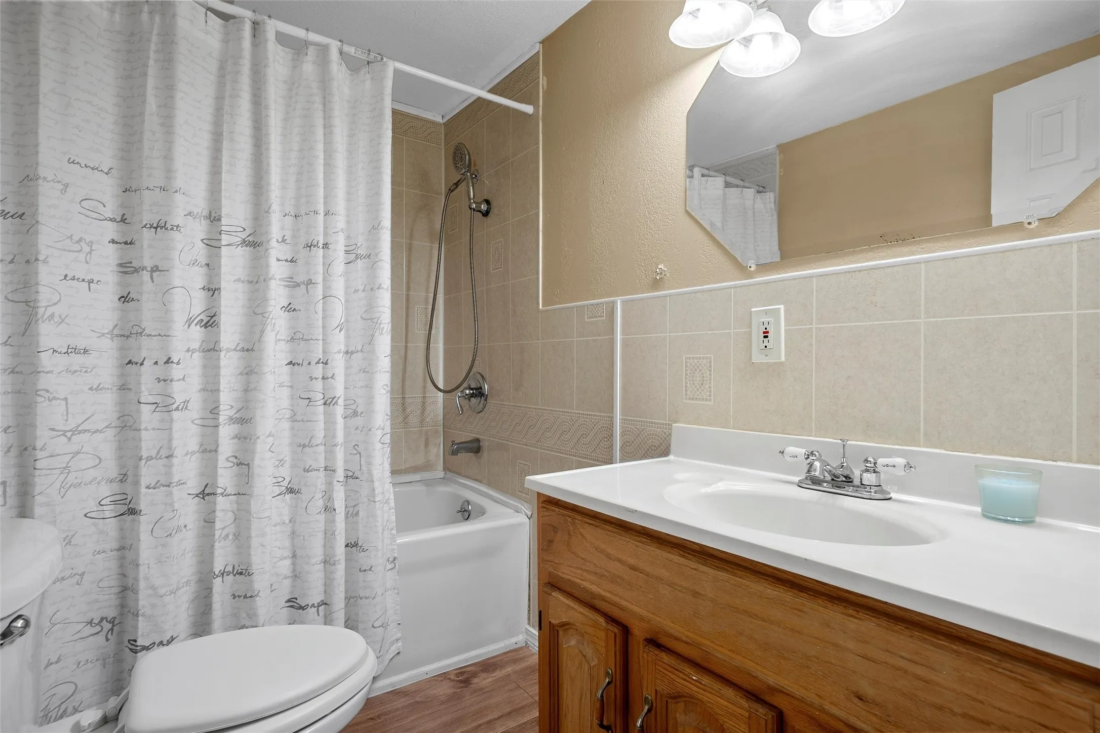 Bathroom featuring a white bathtub, ceramic tile surround, and an integrated shower head with a handheld sprayer