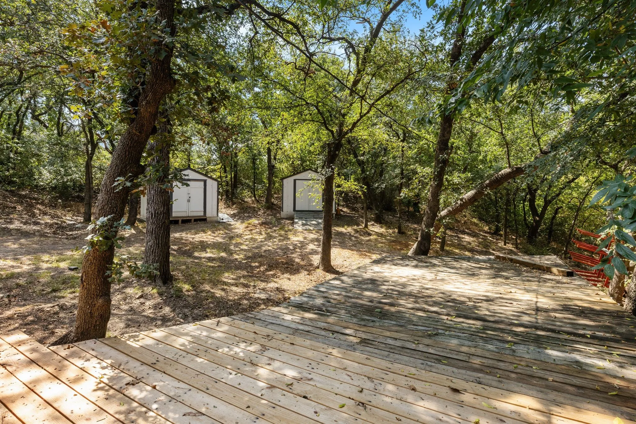 Expansive outdoor decking, multiple storage sheds, and mature trees