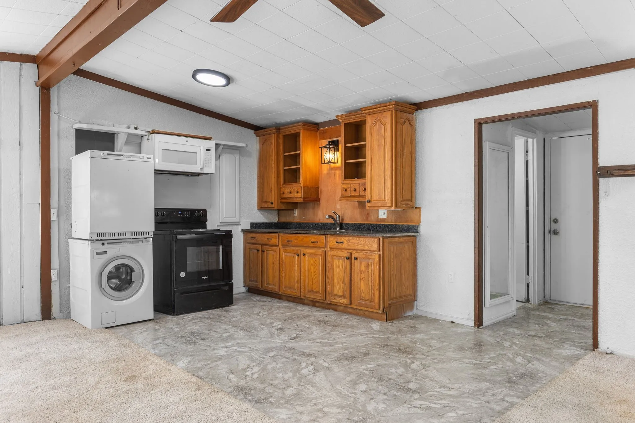 Kitchenette featuring wood-finish cabinetry, black countertops, and a ceiling fan