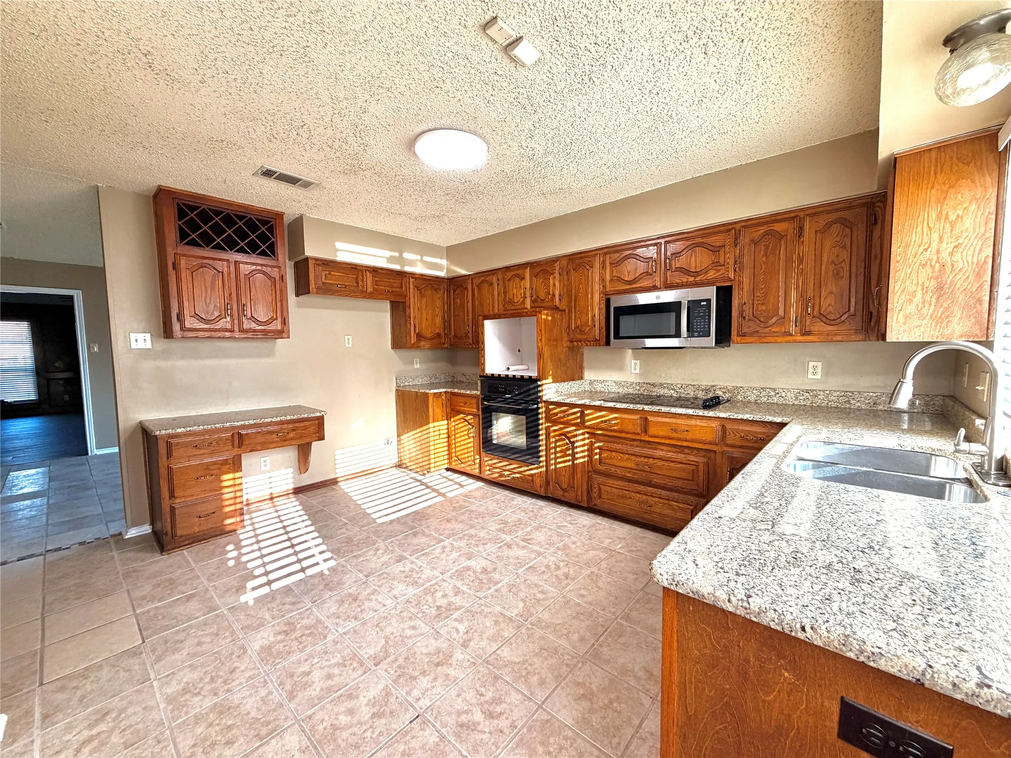 Kitchen featuring wood cabinetry, light-toned countertops, a stainless steel sink, and built-in stainless steel appliances