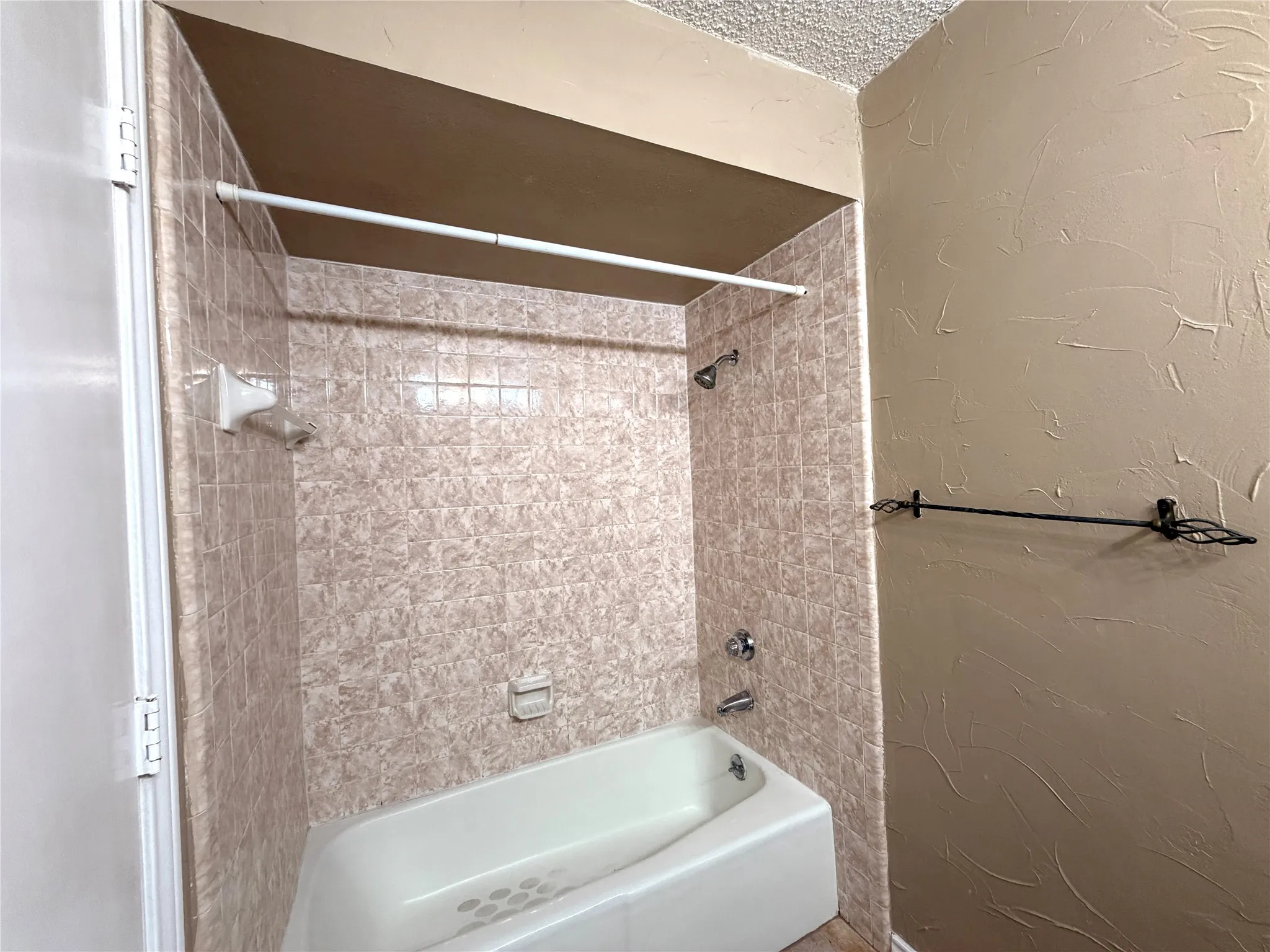 Bathtub with integrated shower features tiled surround and chrome fixtures