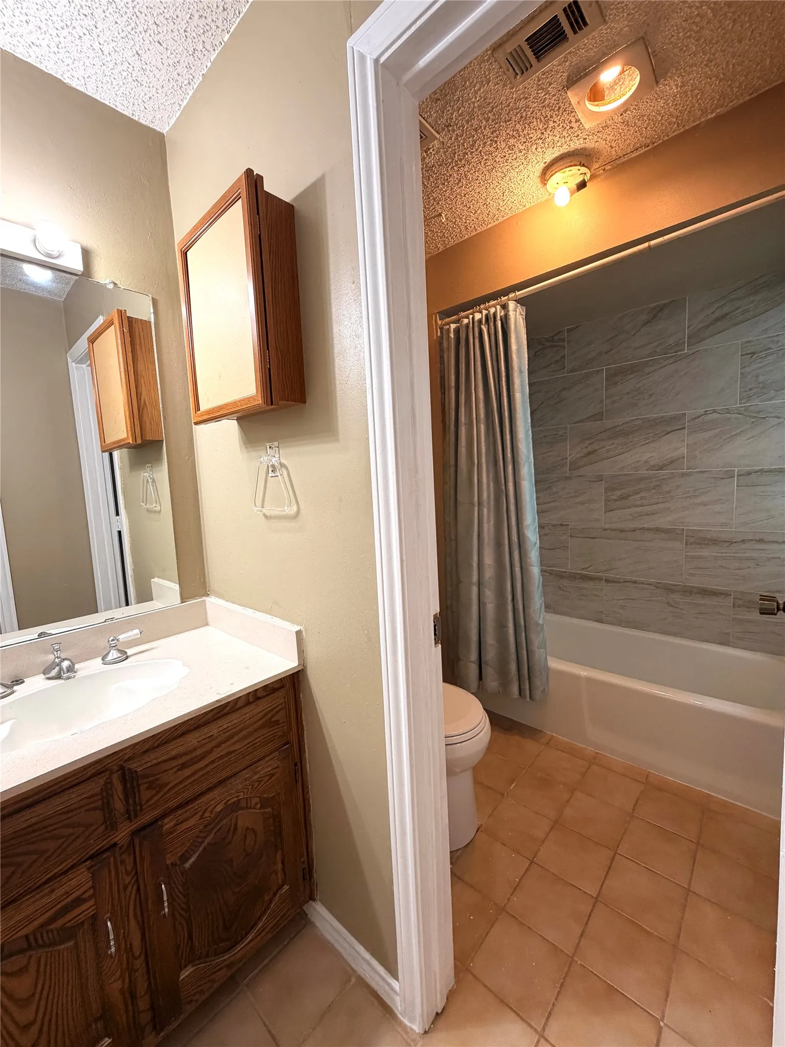 Bathroom with a vanity featuring a wood-finish cabinet and a white countertop with an integrated sink