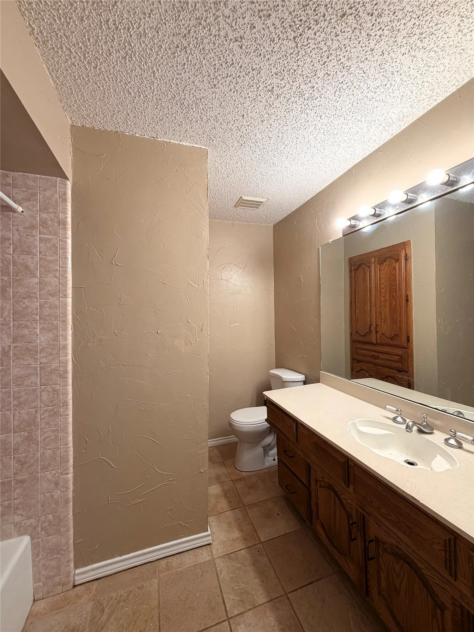 Bathroom featuring a double vanity with an integrated sink, a large mirror, and tile flooring
