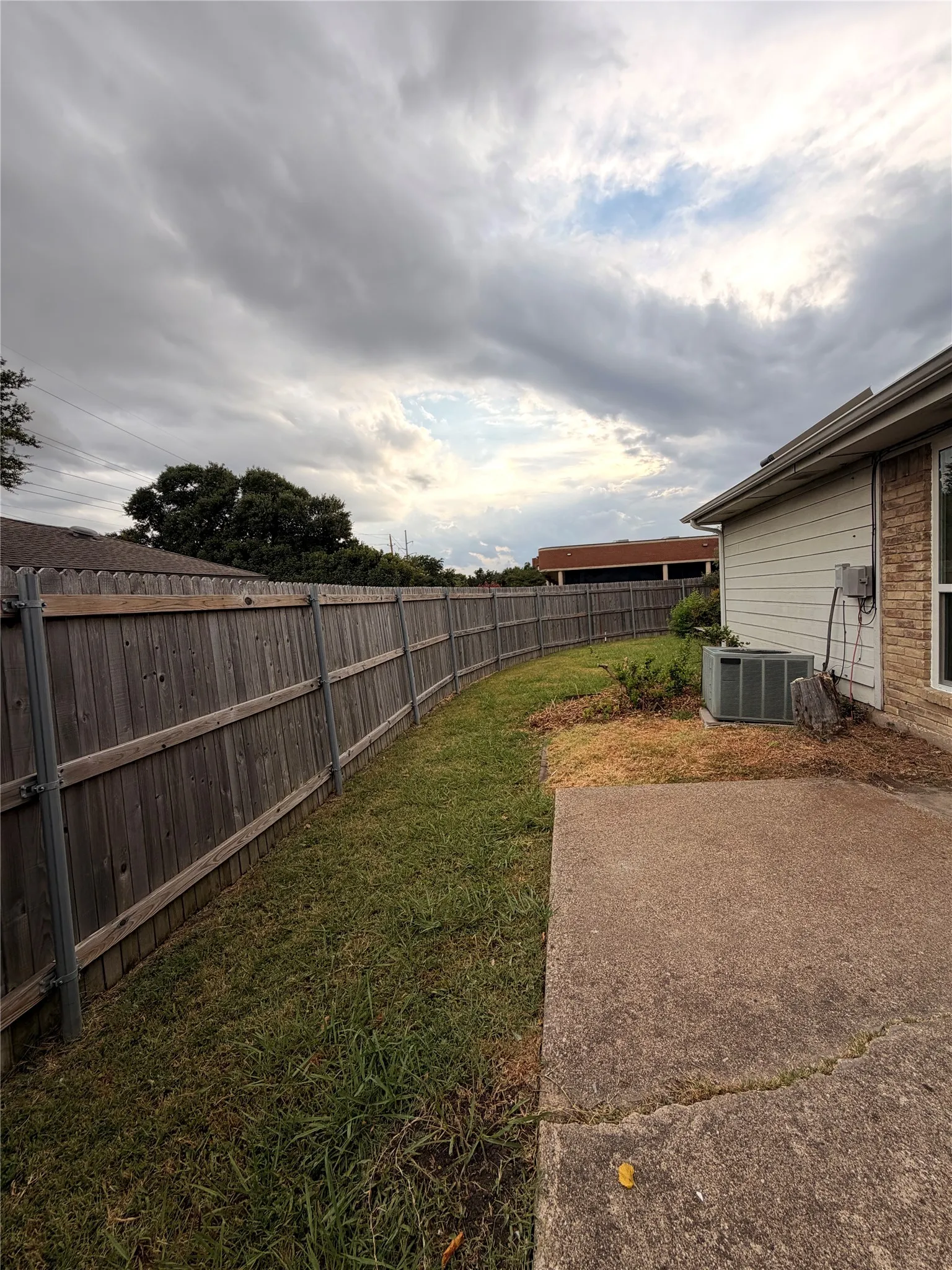 Private backyard featuring a wooden fence, a concrete patio, and a grass lawn
