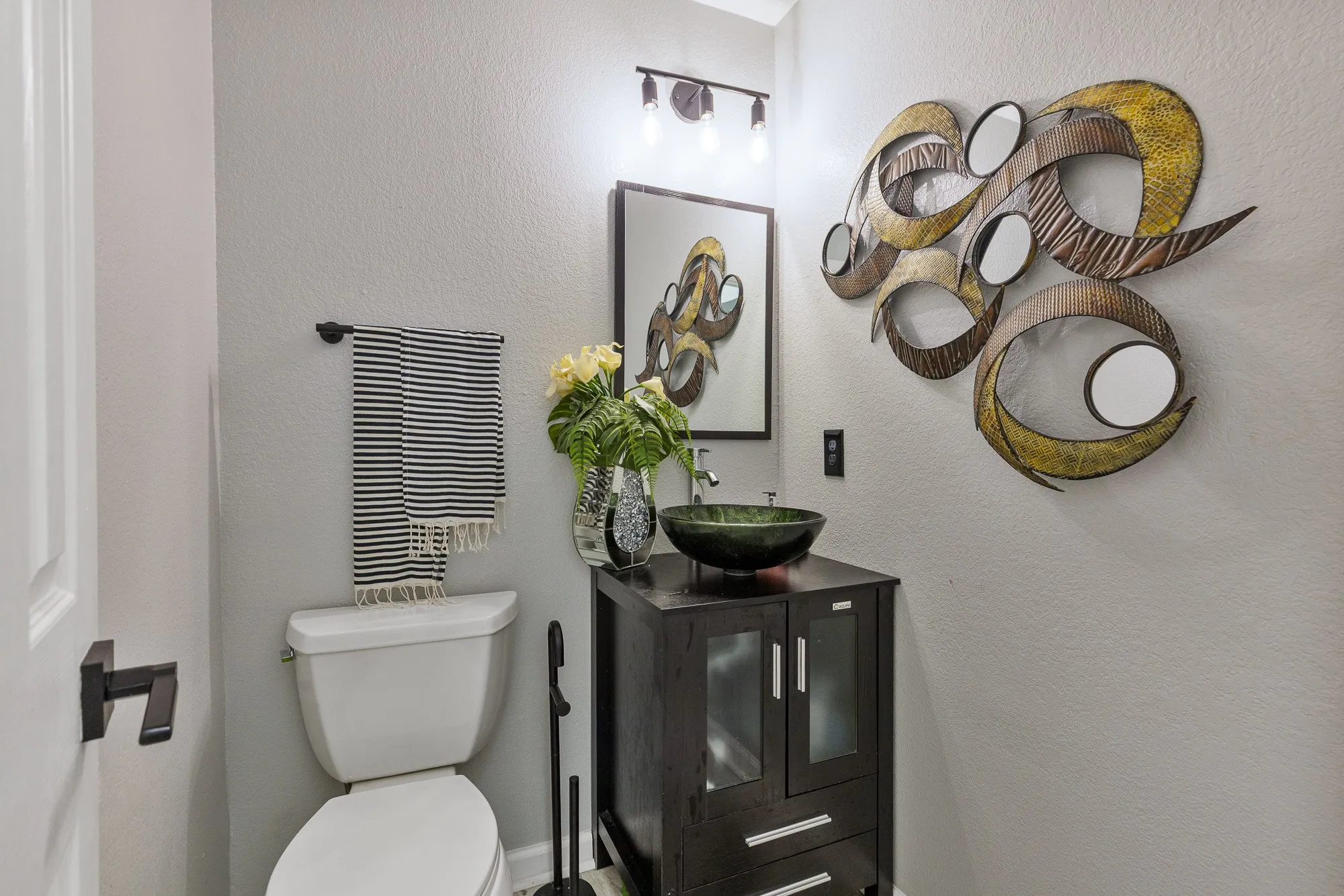 Powder room featuring a dark wood-finish vanity with a green glass vessel sink
