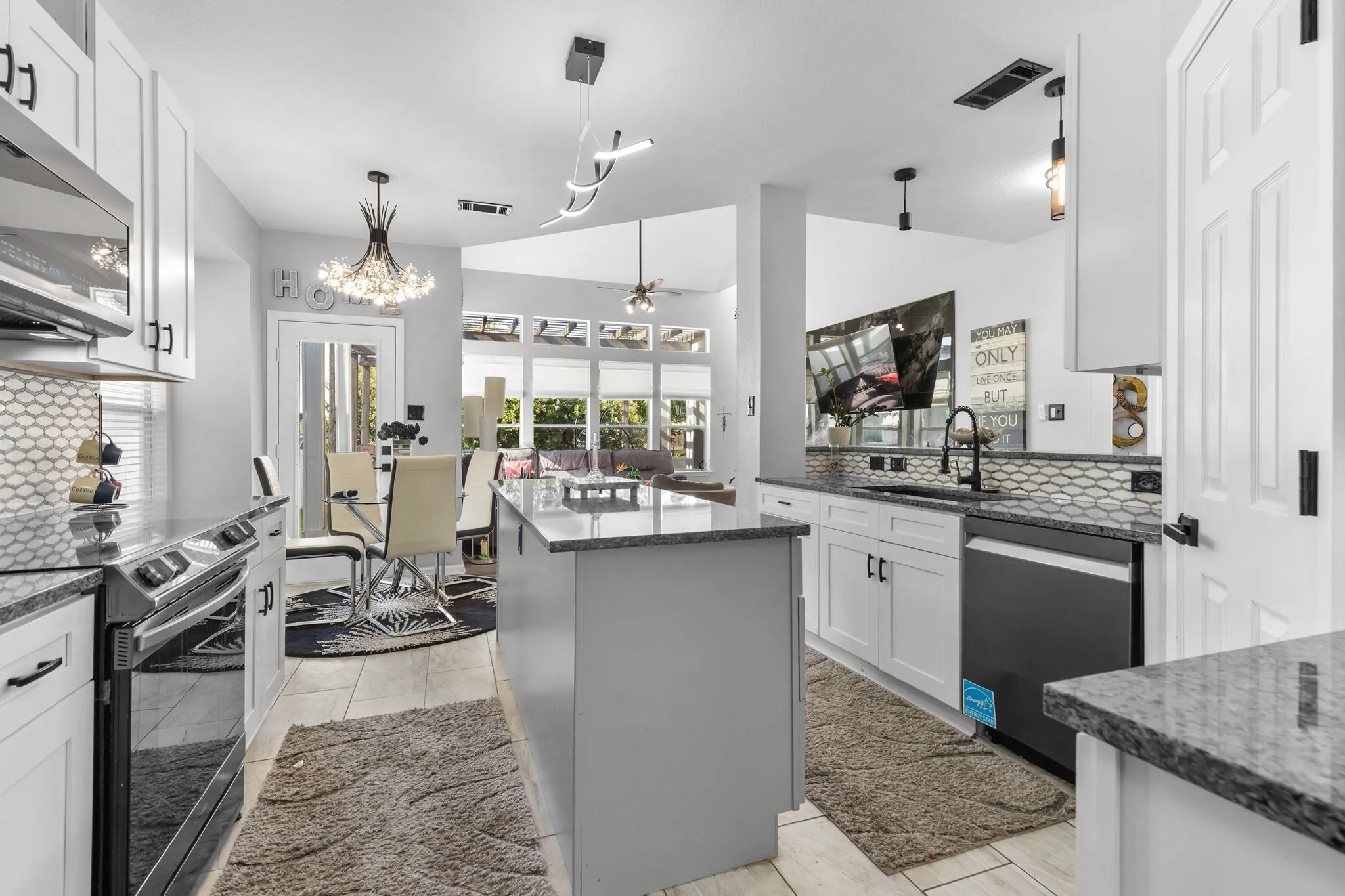 Kitchen featuring granite countertops, white cabinetry with black hardware, a center island, and tile flooring