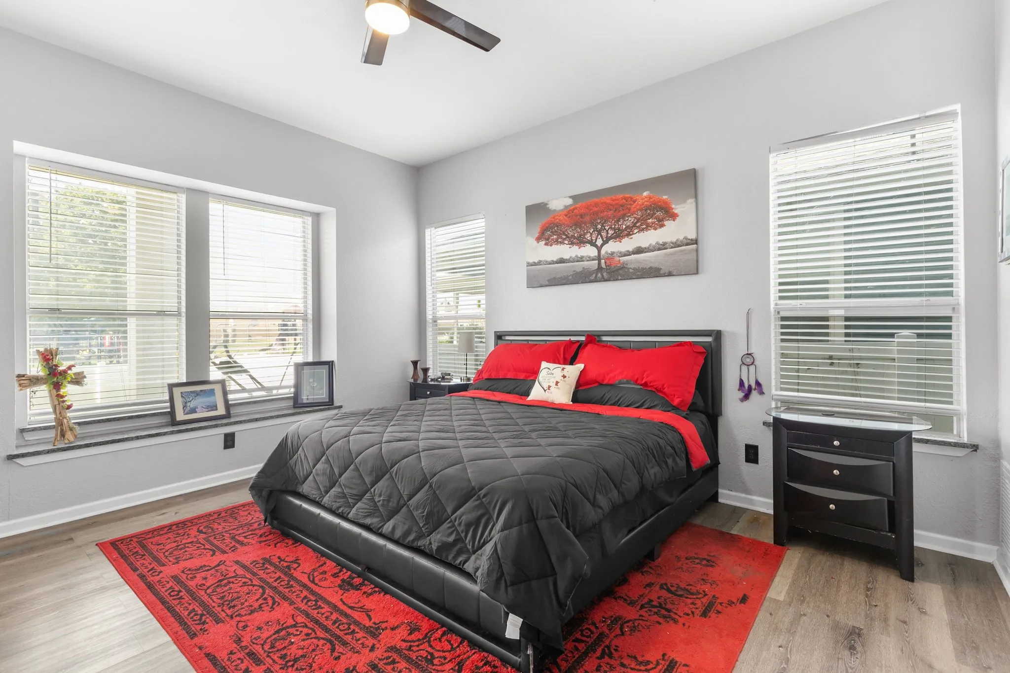 Bedroom featuring multiple windows with horizontal blinds, wood-finish flooring, and a ceiling fan with integrated lighting