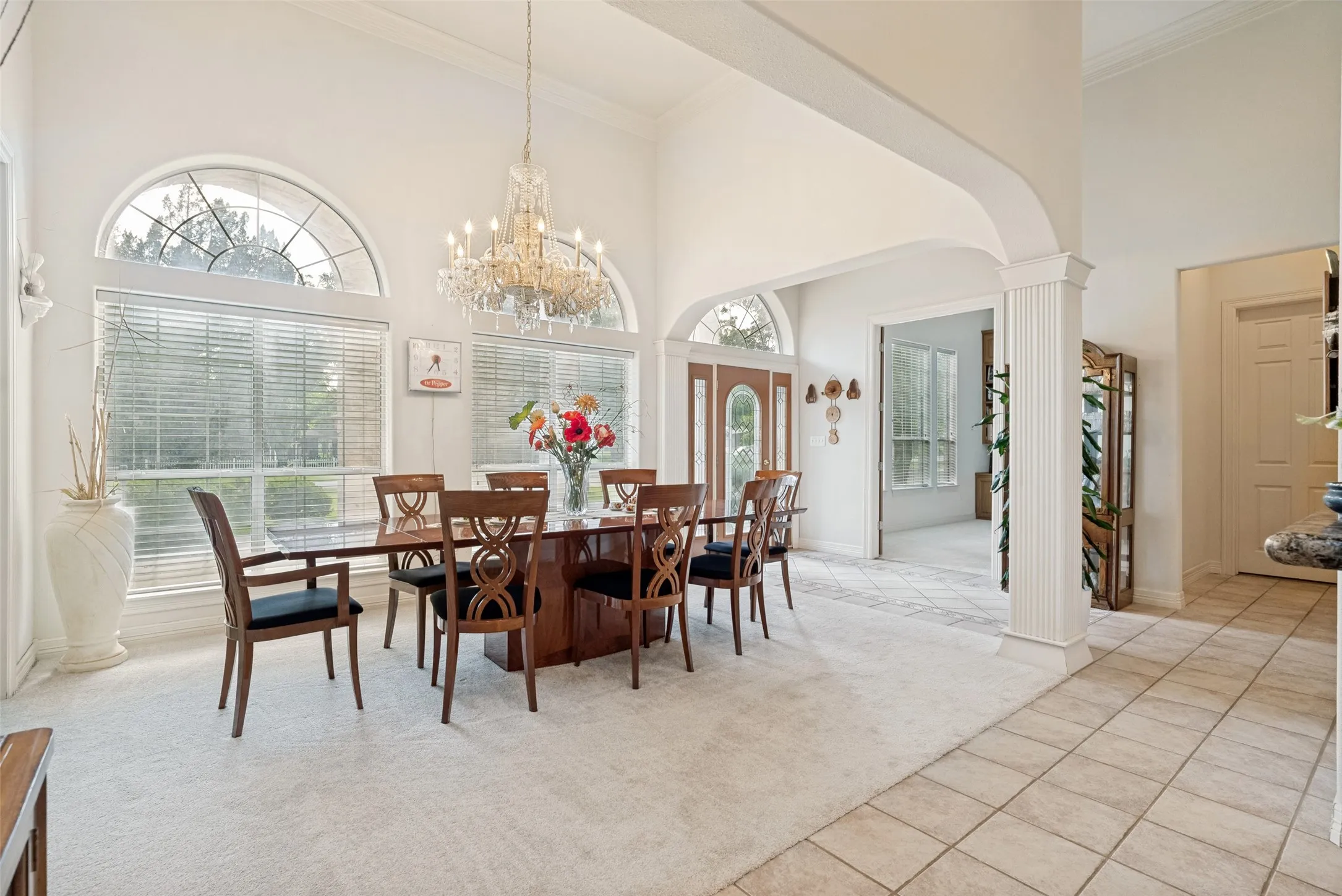  tall ceiling dining area featuring a crystal chandelier, wall of windows, and crown molding