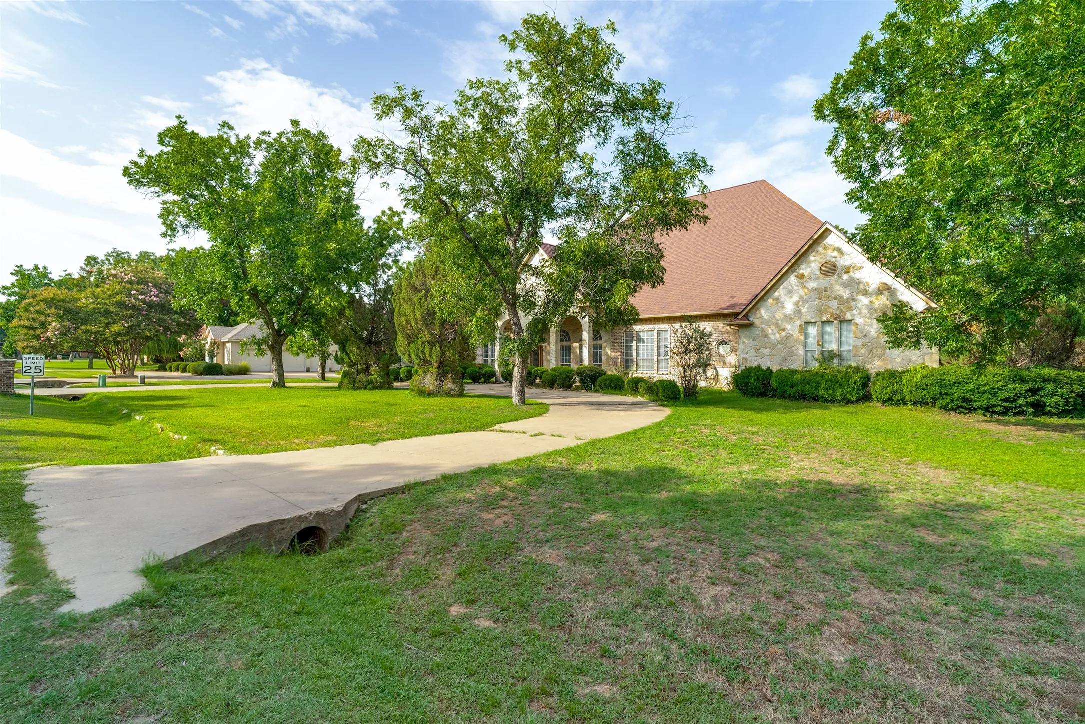 Stone exterior and a curving concrete​​‌​​​​‌​​‌‌​‌‌​​​‌‌​‌​‌​‌​​​‌​​ driveway