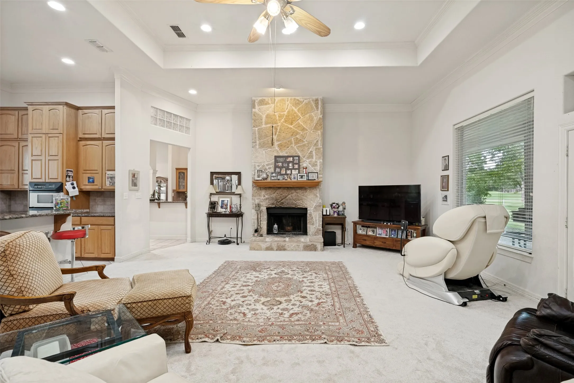 Spacious open living area featuring a stone fireplace, recessed lighting, extra large windows, French doors, and a tray ceiling with a ceiling fan